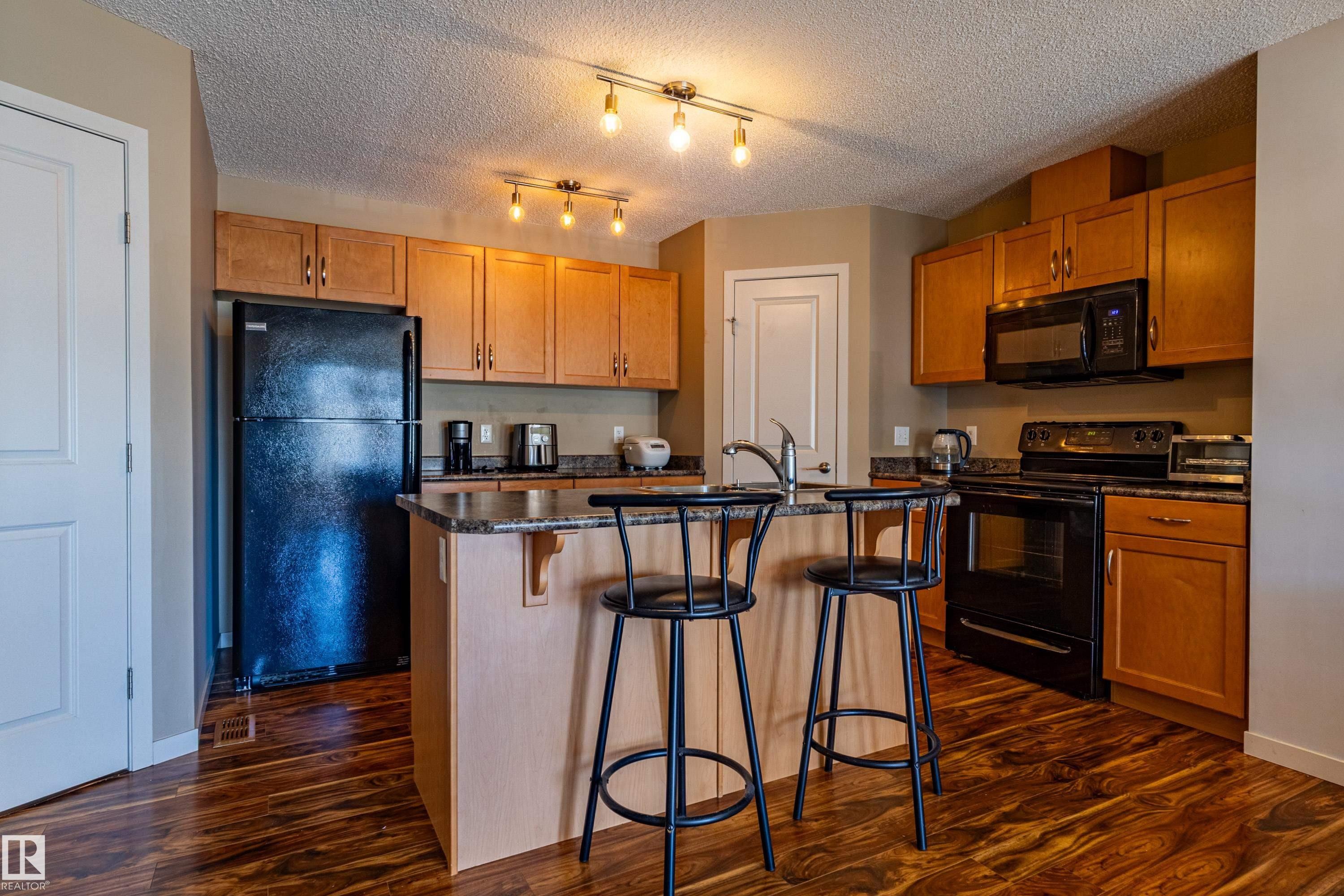 Kitchen with wood-finish flooring, light wood cabinetry, and track lighting - 13 1816 Rutherford Road, Edmonton, AB