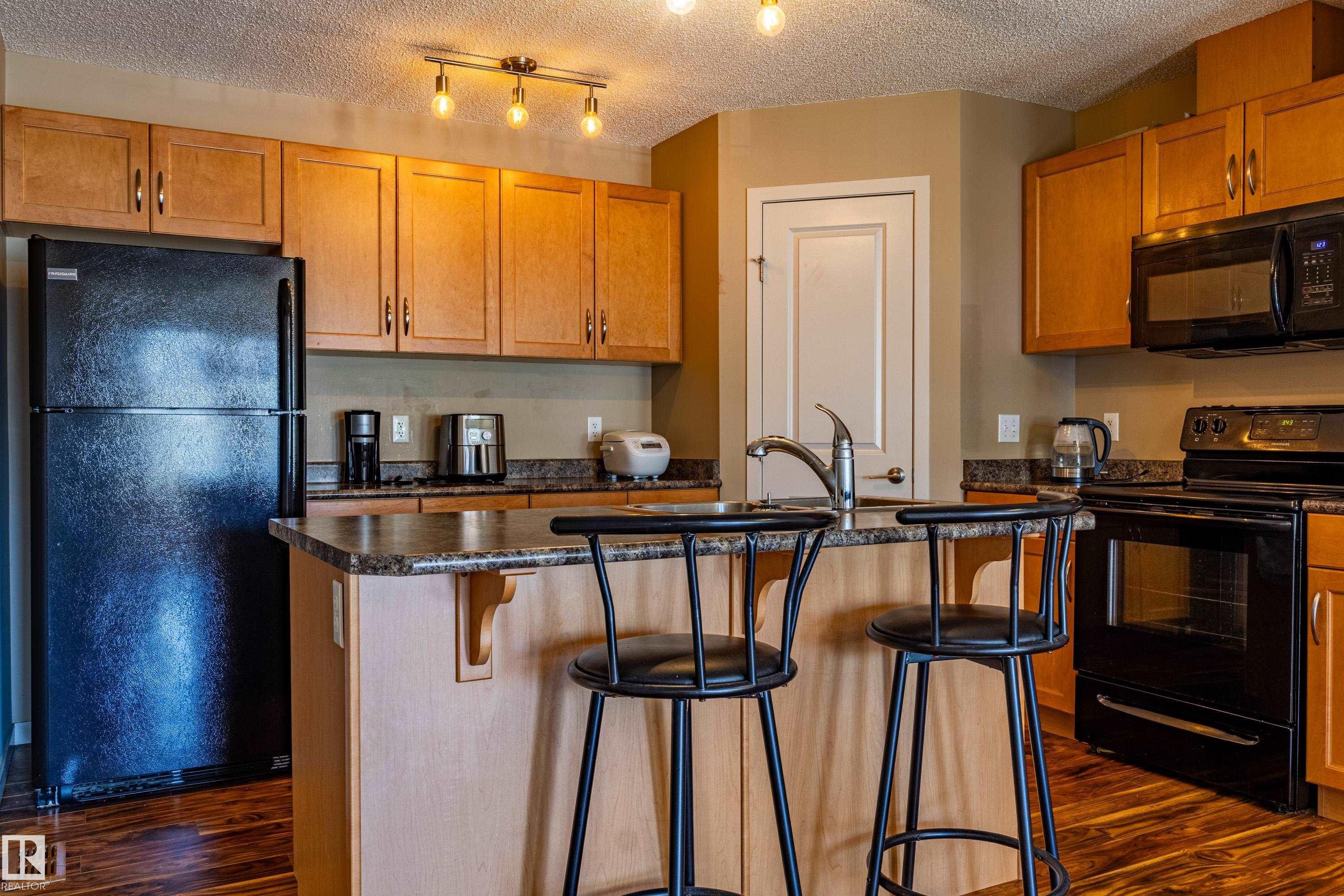 Kitchen featuring wood-finish flooring and light wood cabinetry - 13 1816 Rutherford Road, Edmonton, AB