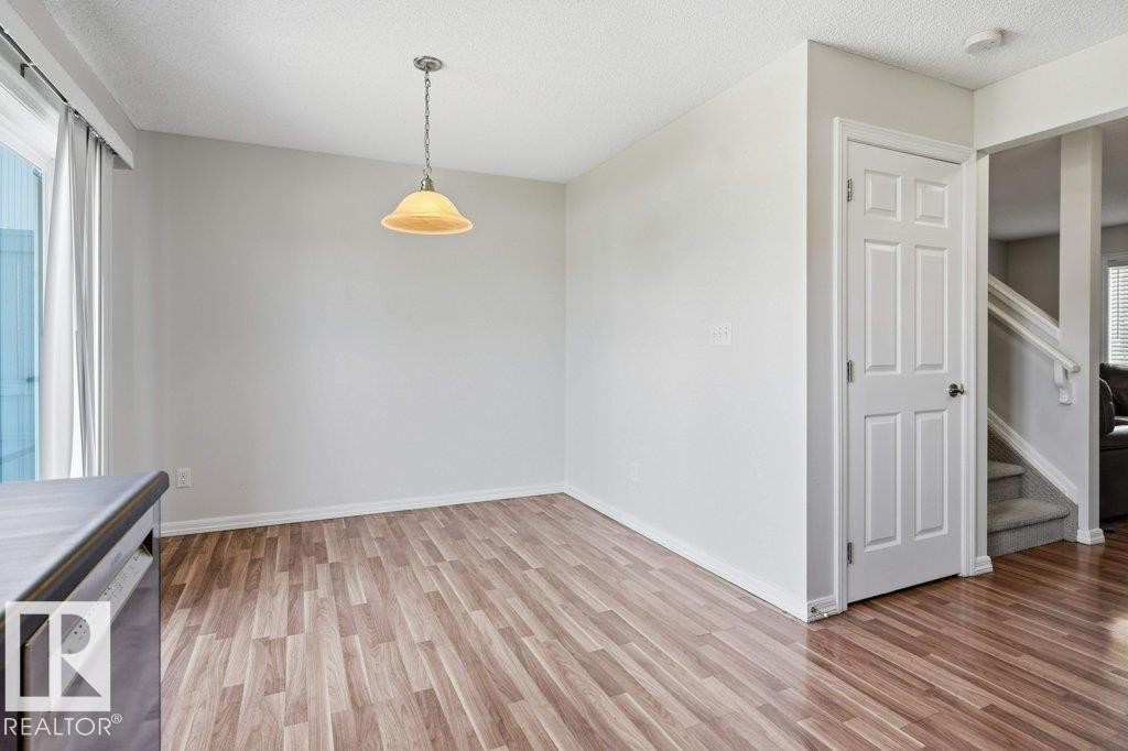 Dining area featuring wood-finish flooring, a pendant light fixture, and neutral wall tones - 30 1404 Hermitage Road, Edmonton, AB