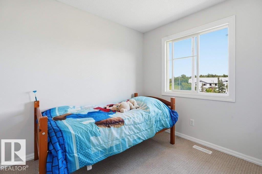 Bright room featuring a large window with white trim, light gray walls, and neutral carpeting - 30 1404 Hermitage Road, Edmonton, AB