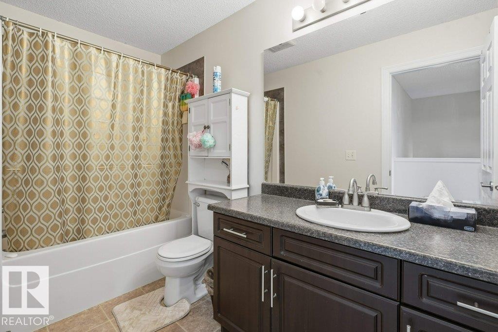 Bathroom featuring a dark wood-finish vanity with a single basin, grey flecked countertop, and brushed nickel fixtures - 30 1404 Hermitage Road, Edmonton, AB