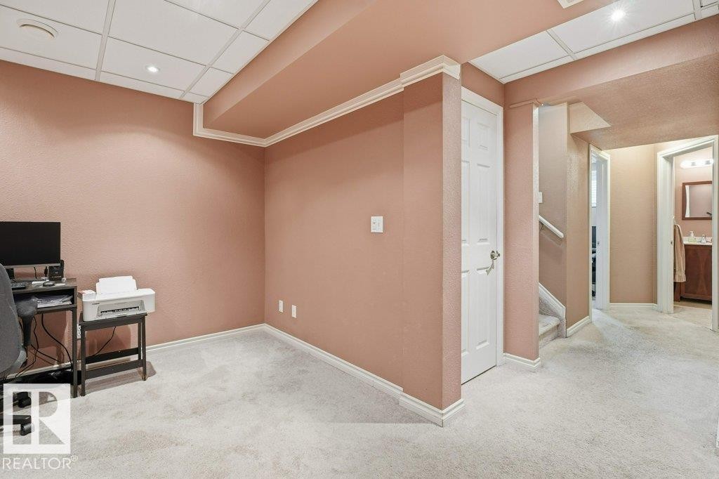 Carpeted room featuring a drop ceiling with recessed lighting, crown molding, and a paneled door - 30 1404 Hermitage Road, Edmonton, AB