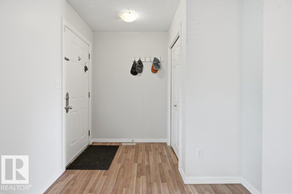 Entryway featuring wood-finish flooring, a flush-mount ceiling light fixture, and a built-in coat rack - 30 1404 Hermitage Road, Edmonton, AB