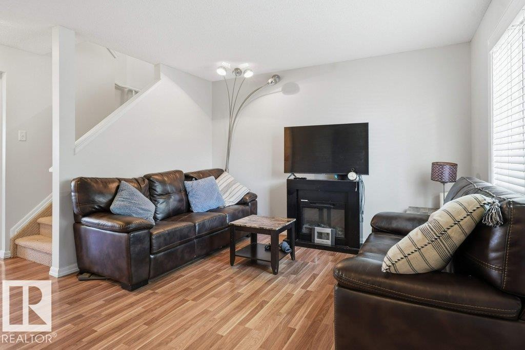 Bright living area featuring wood-finish flooring and a staircase with carpeted treads - 30 1404 Hermitage Road, Edmonton, AB