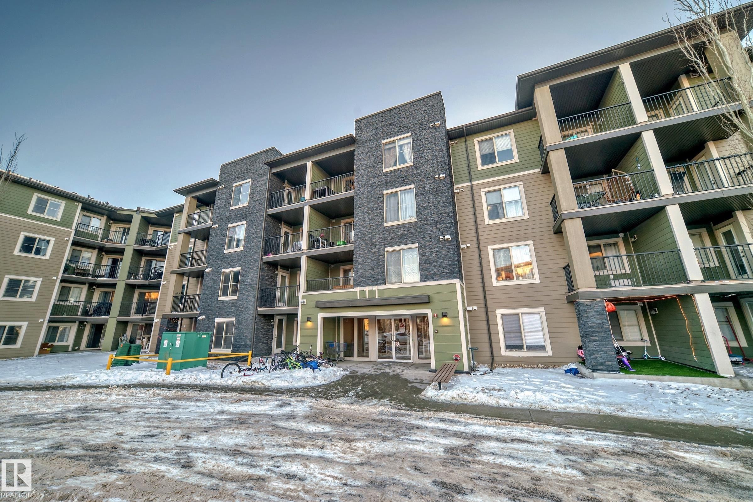 Multi-story residential building featuring a stone and siding exterior - #121 111 Watt Cm Sw, Edmonton, AB - Outdoor With Facade