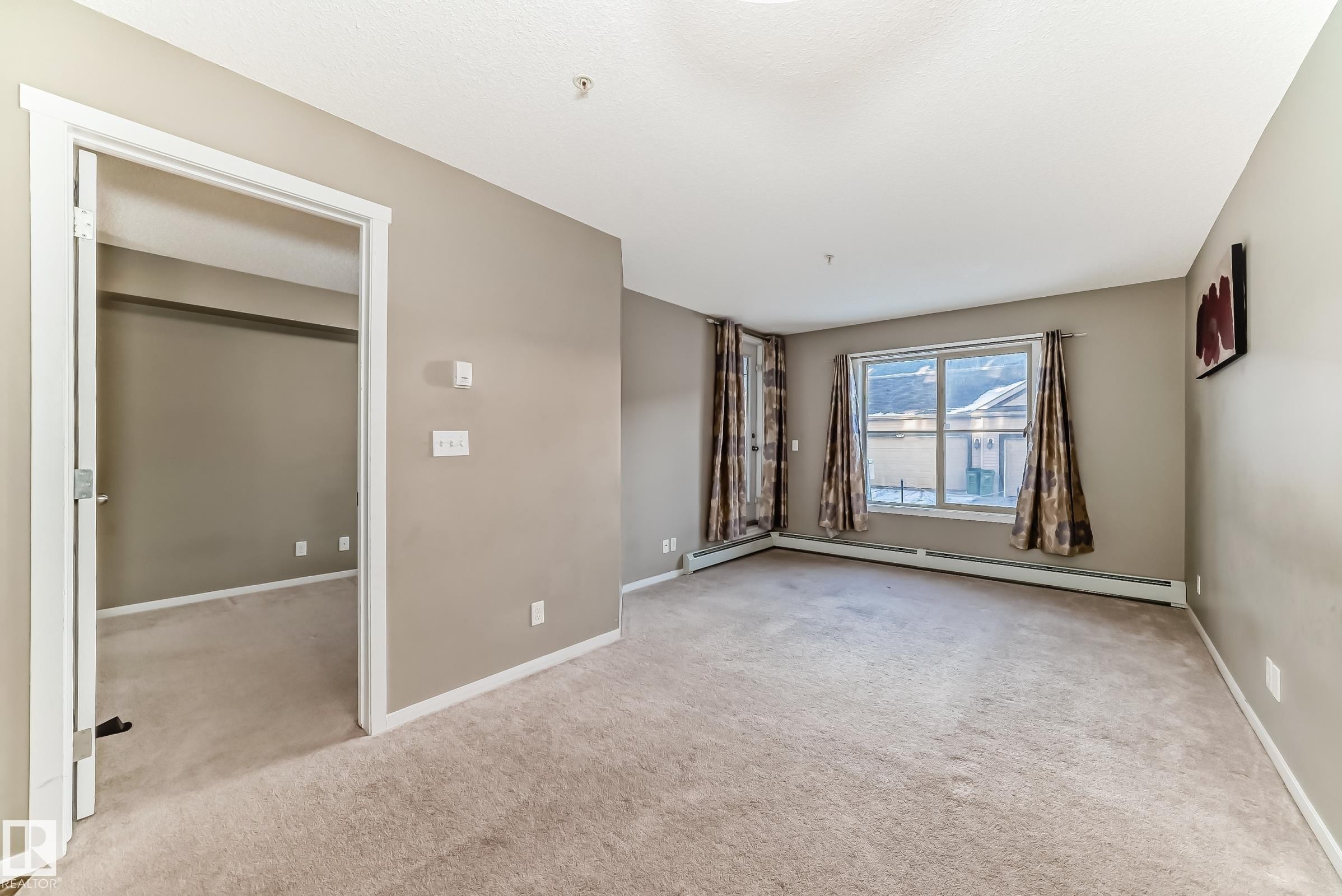 Neutral-toned room with plush carpeting and a large window - #121 111 Watt Cm Sw, Edmonton, AB - Indoor Photo Showing Other Room