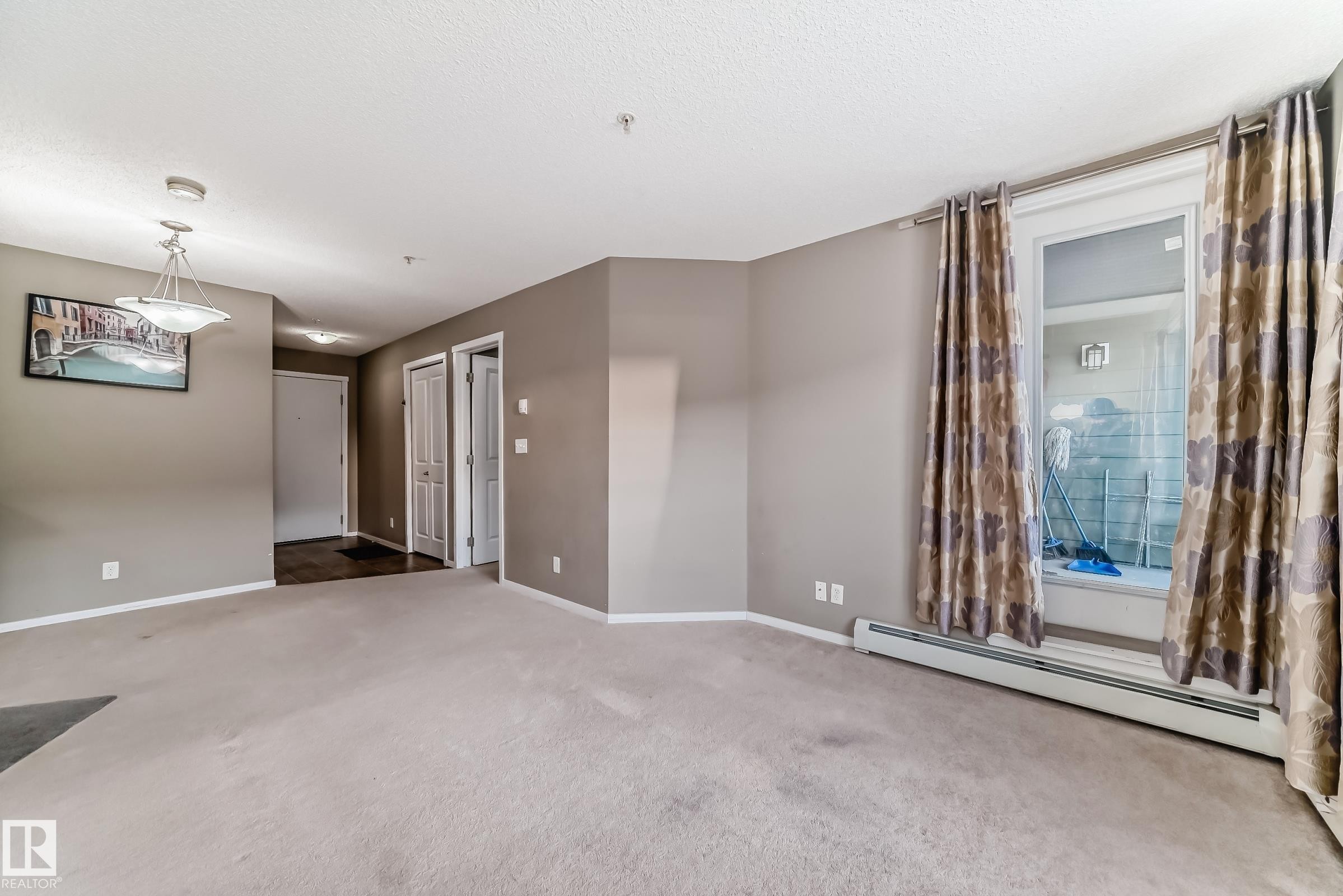 Carpeted living area featuring a large window, neutral paint colors, and a ceiling-mounted light fixture - #121 111 Watt Cm Sw, Edmonton, AB - Indoor Photo Showing Other Room