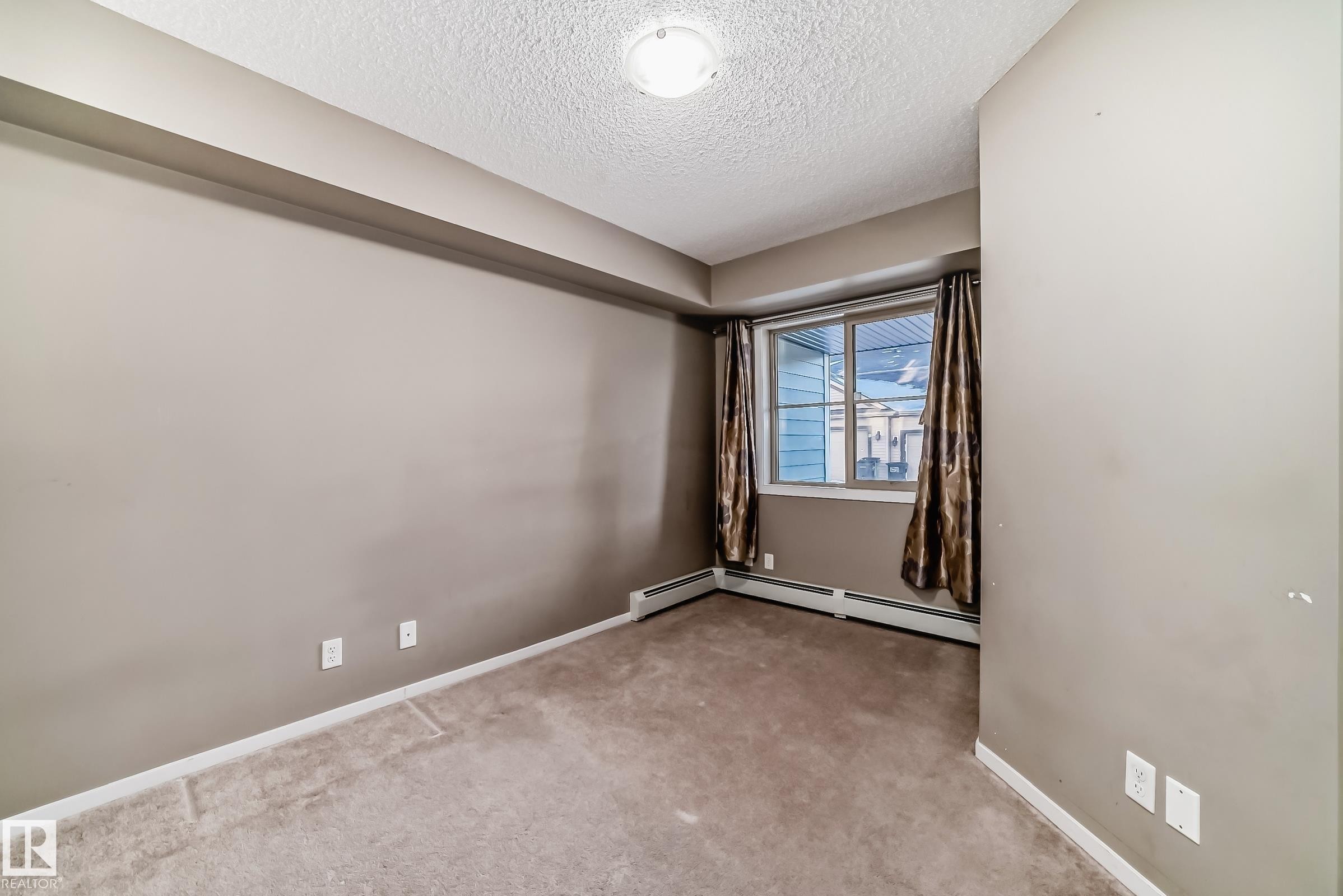 Carpeted interior room with neutral-toned walls, white trim, and a window with horizontal blinds - #121 111 Watt Cm Sw, Edmonton, AB - Indoor Photo Showing Other Room
