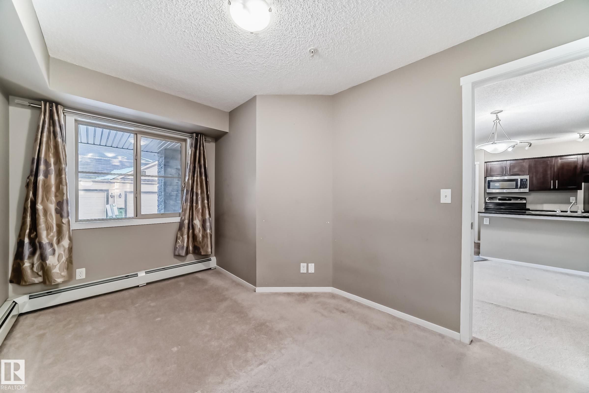 Bright room with neutral carpet flooring and a large window - #121 111 Watt Cm Sw, Edmonton, AB - Indoor Photo Showing Other Room
