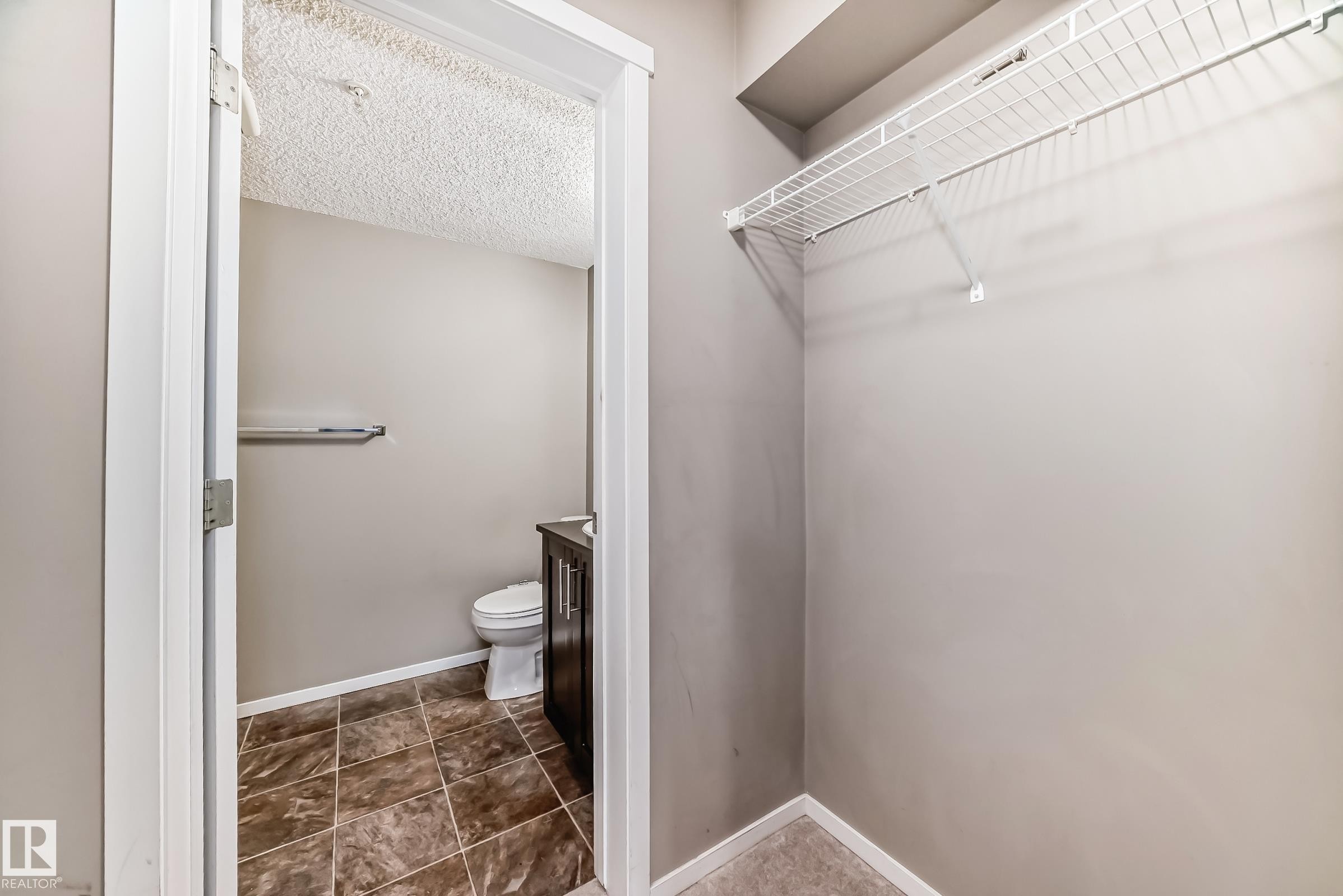 Compact powder room featuring a dark wood-finish vanity with a white countertop and a tiled floor - #121 111 Watt Cm Sw, Edmonton, AB - Indoor
