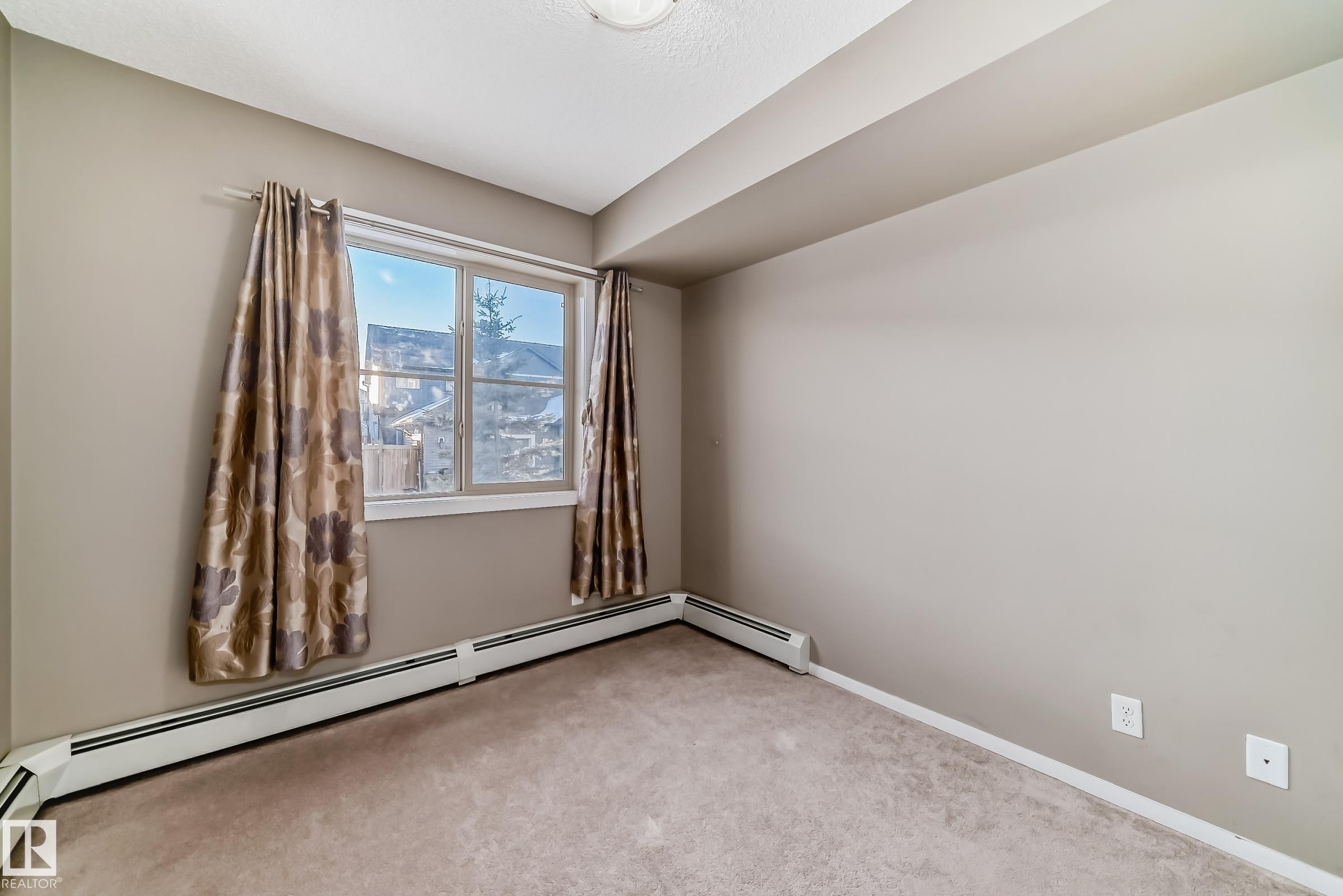 Room featuring wall-to-wall carpeting, light neutral wall paint, and baseboard heating - #121 111 Watt Cm Sw, Edmonton, AB - Indoor Photo Showing Other Room