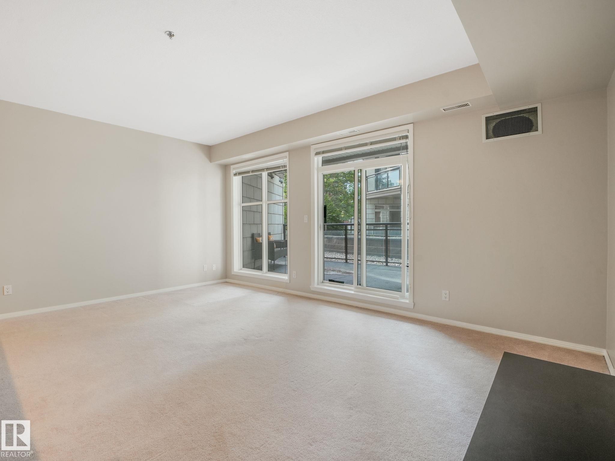 Expansive living area featuring light-toned carpeting and neutral wall paint - 150 4827 104A Street, Edmonton, AB
