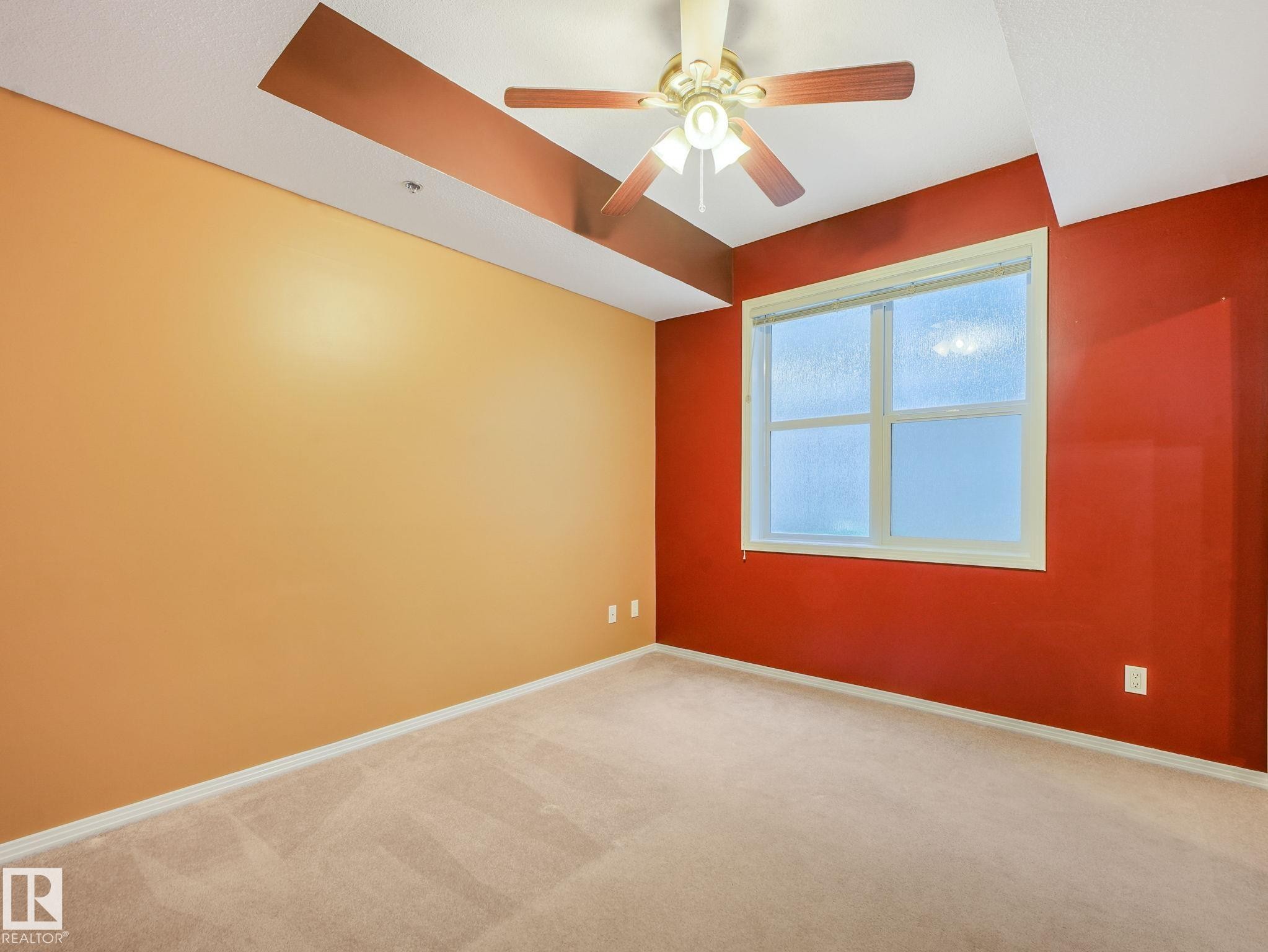 Bright room featuring neutral carpeting, a large window, and a ceiling fan with light fixture - 150 4827 104A Street, Edmonton, AB