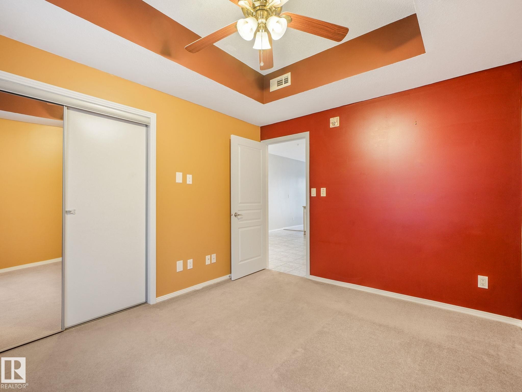 Carpeted room featuring a ceiling fan with light fixture, tray ceiling detail, and two-tone wall finishes - 150 4827 104A Street, Edmonton, AB