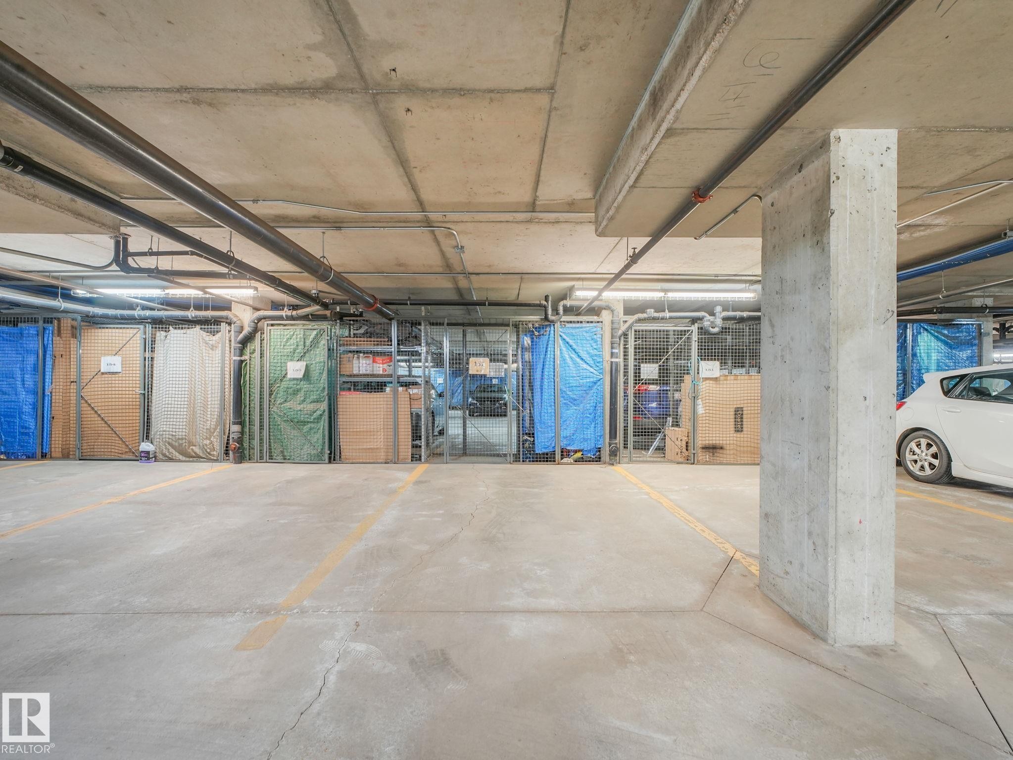 Underground parking garage featuring concrete flooring, exposed concrete ceiling, and support columns - 150 4827 104A Street, Edmonton, AB