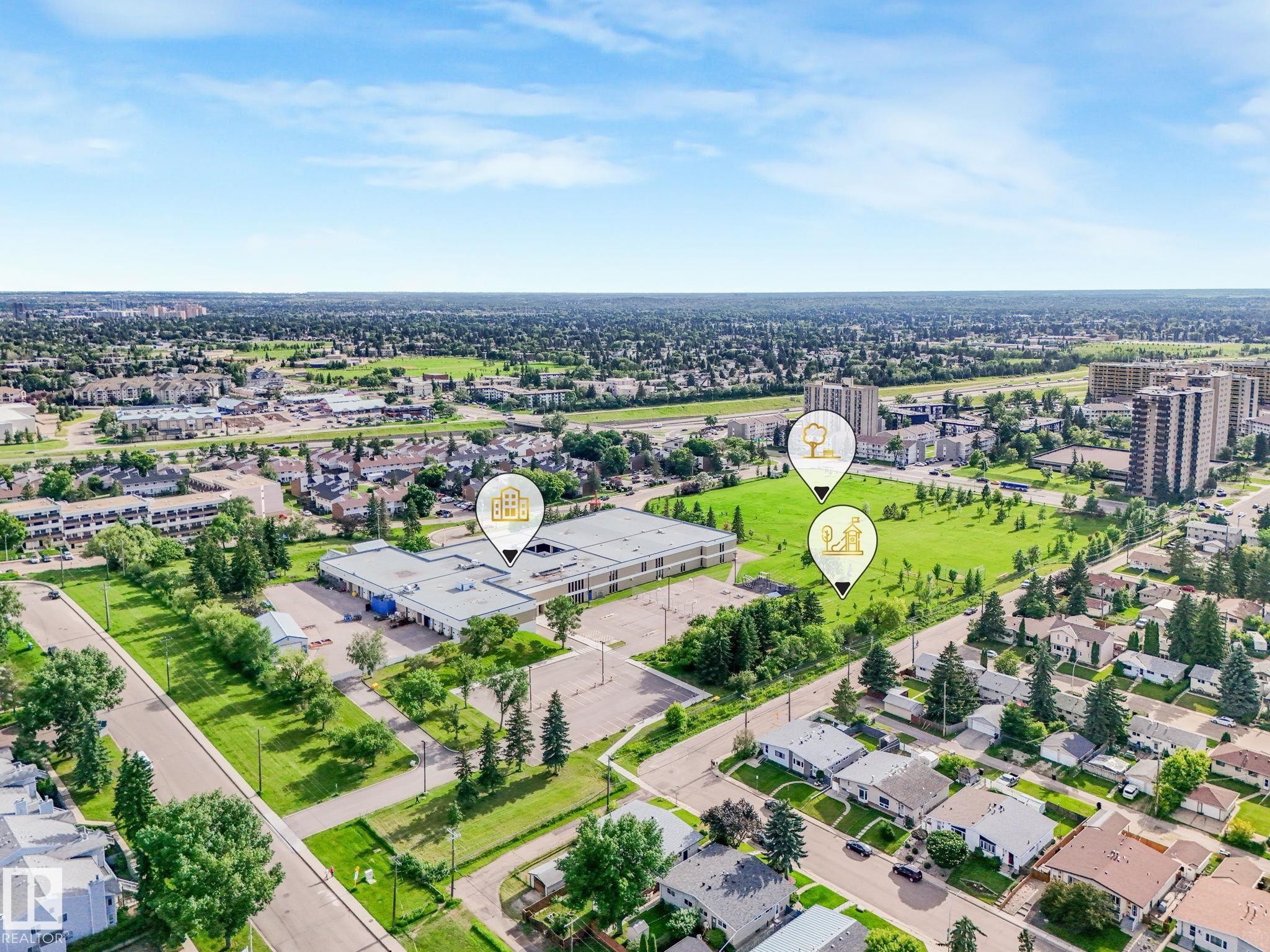 Aerial perspective showcasing a developed neighborhood with residential properties, commercial structures, and green spaces - 150 4827 104A Street, Edmonton, AB