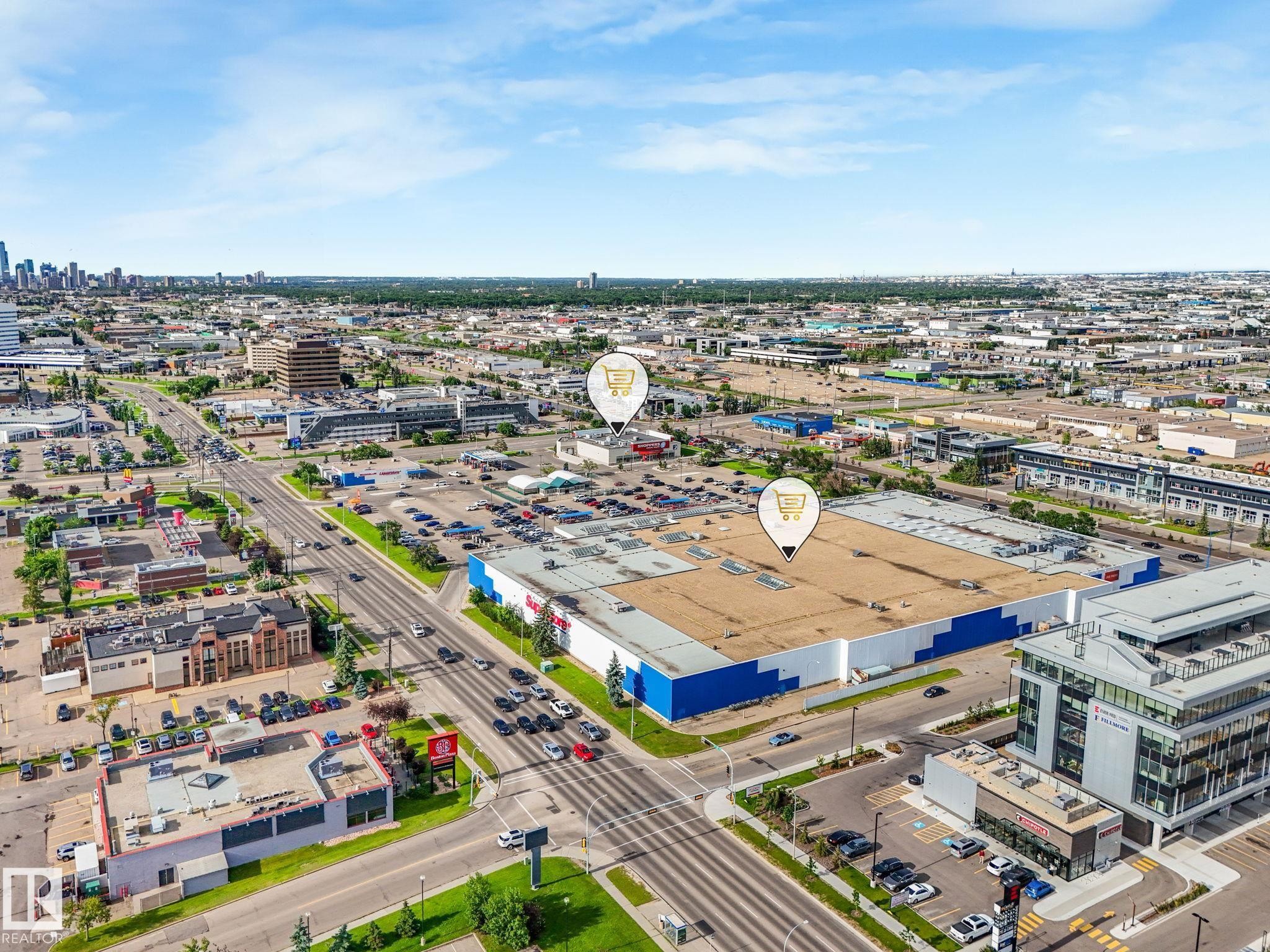 Expansive commercial property featuring a large-format retail building with a blue and white facade, extensive surface parking, and multiple access points - 150 4827 104A Street, Edmonton, AB