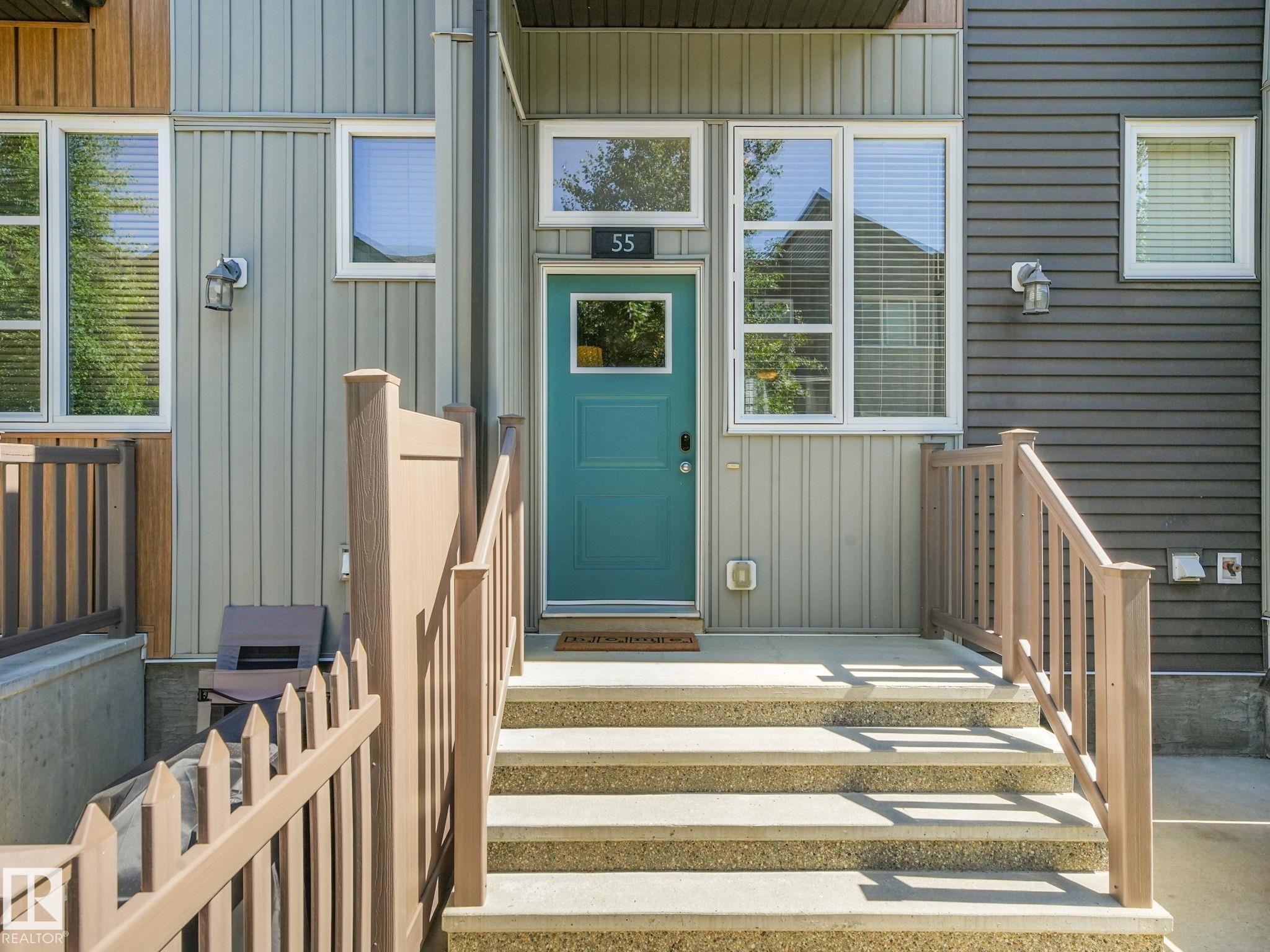 Entryway featuring a teal door with a transom window, concrete steps, and composite railings - #55 4470 Prowse Rd Sw, Edmonton, AB - Outdoor With Exterior