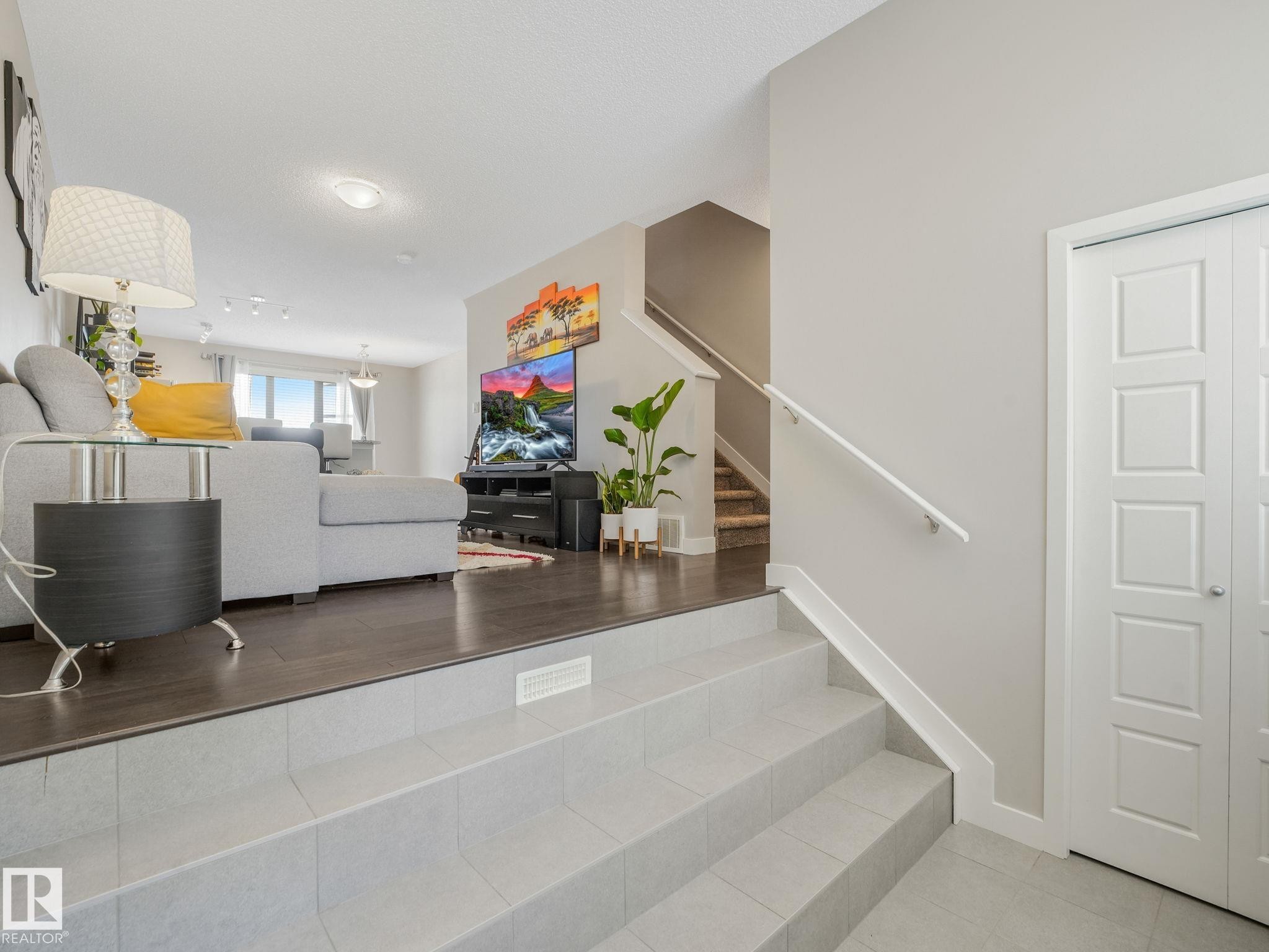Split-level entry featuring light gray floor tiles and a white handrail - #55 4470 Prowse Rd Sw, Edmonton, AB - Indoor Photo Showing Other Room
