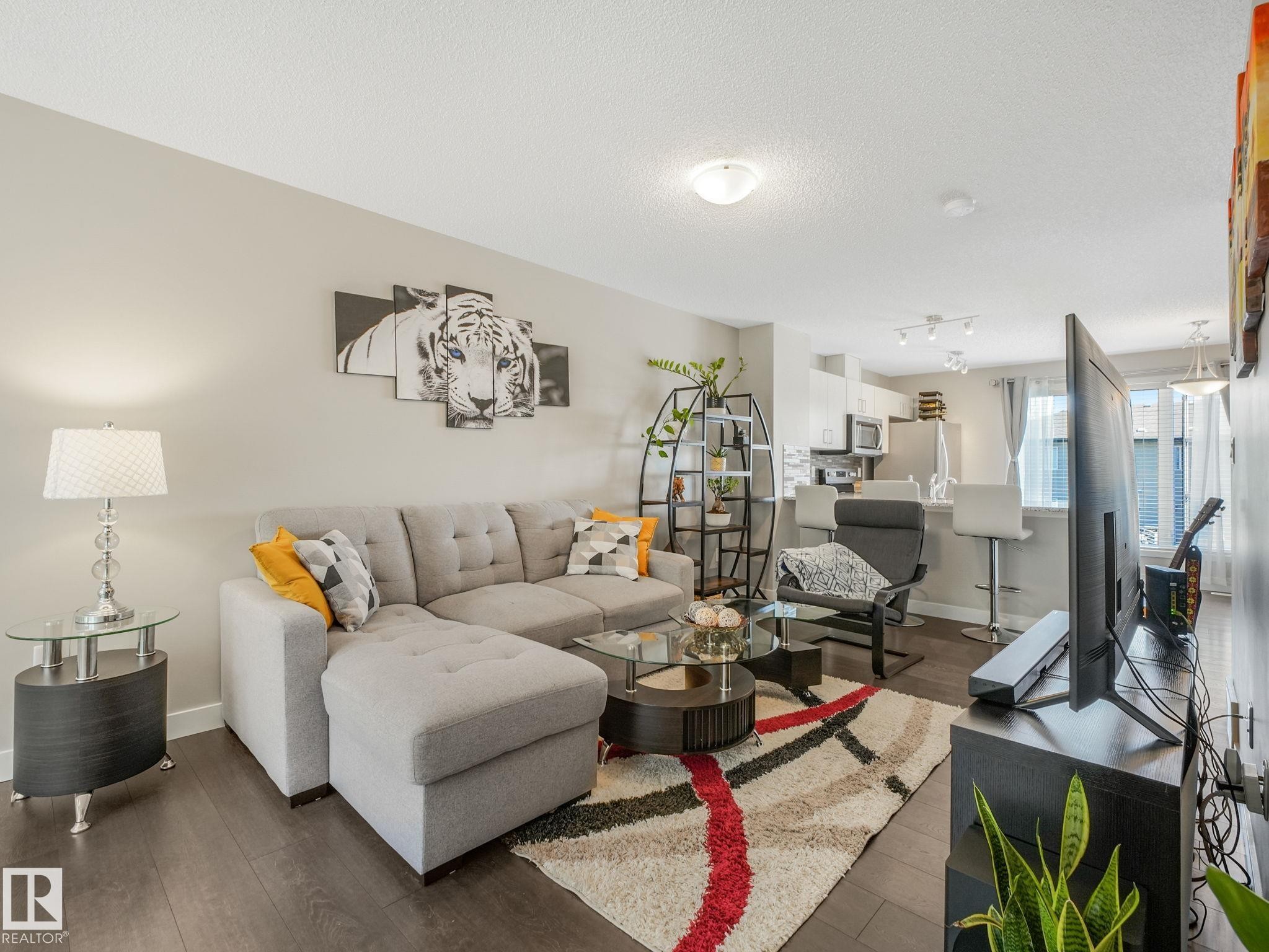 Open-concept living space featuring wood-finish flooring, recessed lighting, and a neutral color palette - #55 4470 Prowse Rd Sw, Edmonton, AB - Indoor Photo Showing Living Room