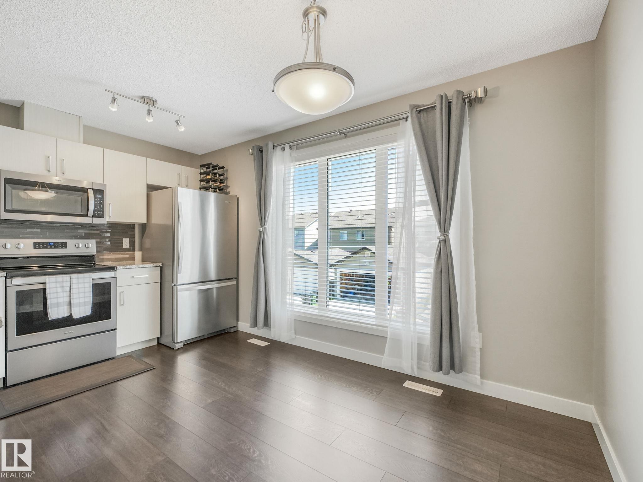 Kitchen dining area featuring dark wood-finish flooring - #55 4470 Prowse Rd Sw, Edmonton, AB - Indoor Photo Showing Kitchen With Stainless Steel Kitchen