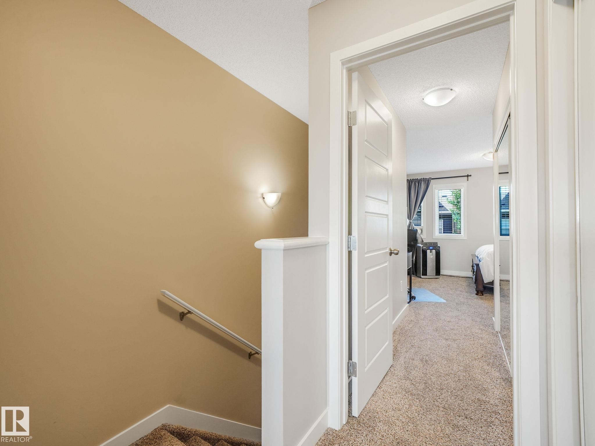 Bright hallway featuring neutral-toned carpeting and a modern flush-mount ceiling light - #55 4470 Prowse Rd Sw, Edmonton, AB - Indoor Photo Showing Other Room