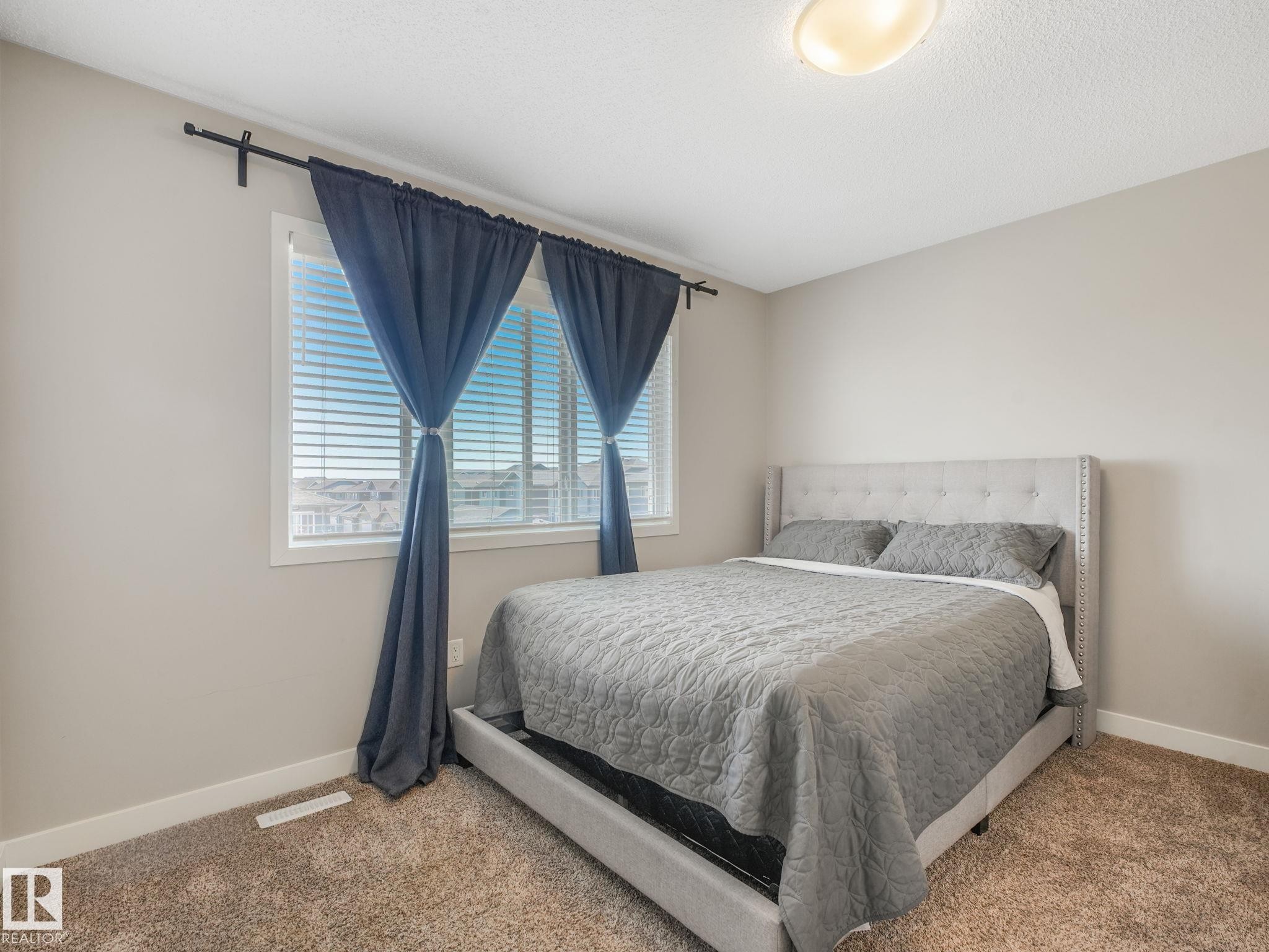 Neutral-toned room featuring a large window with white blinds - #55 4470 Prowse Rd Sw, Edmonton, AB - Indoor Photo Showing Bedroom