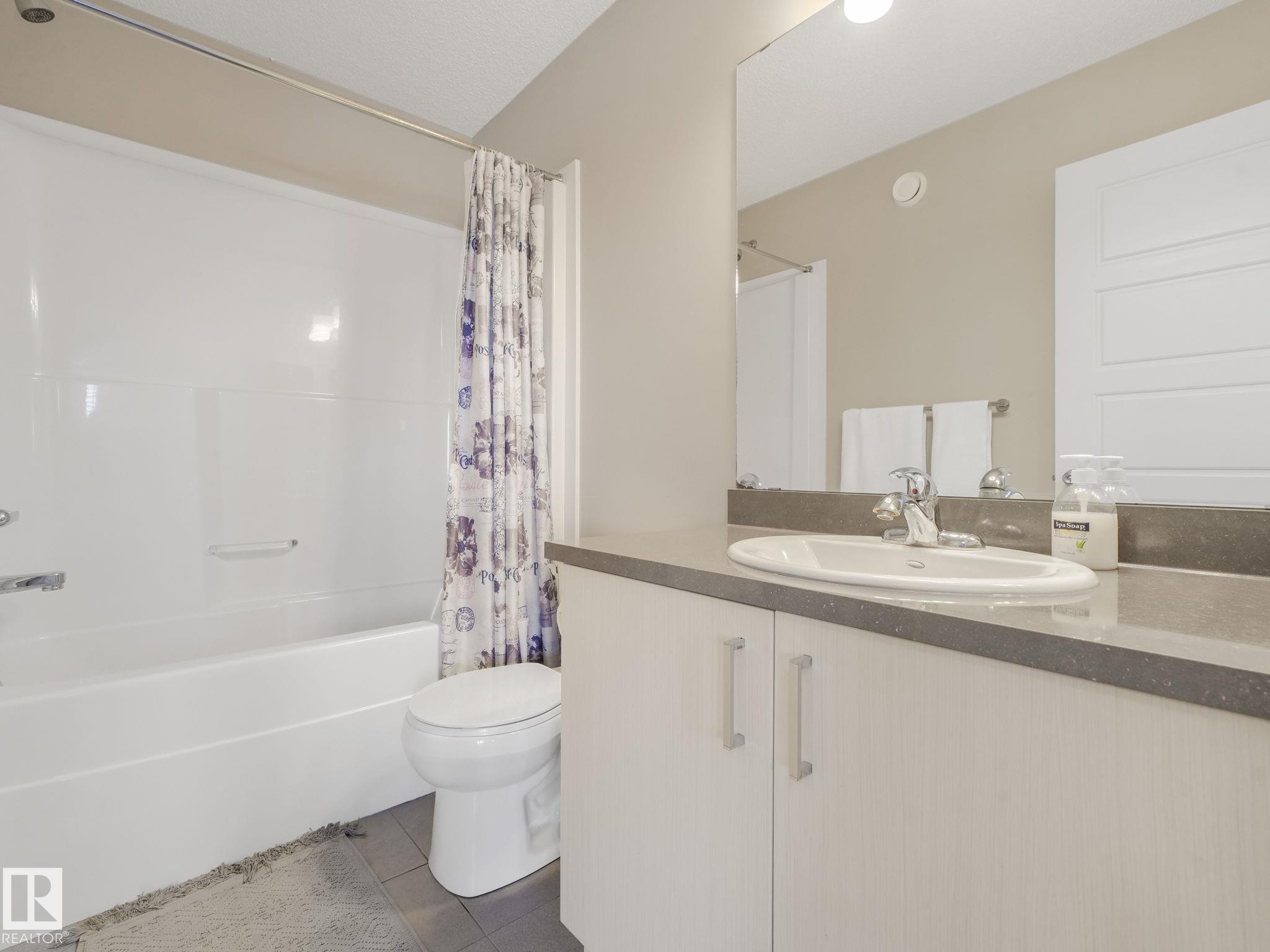 Full bathroom featuring a white tub/shower combination, white toilet, and a vanity with a white basin sink, polished chrome faucet, and integrated countertop - #55 4470 Prowse Rd Sw, Edmonton, AB - Indoor Photo Showing Bathroom