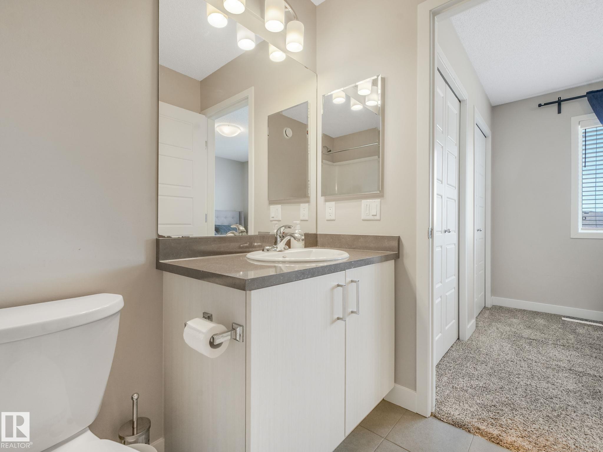 Vanity with a single basin sink, wall-mounted mirror, and vanity lighting - #55 4470 Prowse Rd Sw, Edmonton, AB - Indoor Photo Showing Bathroom