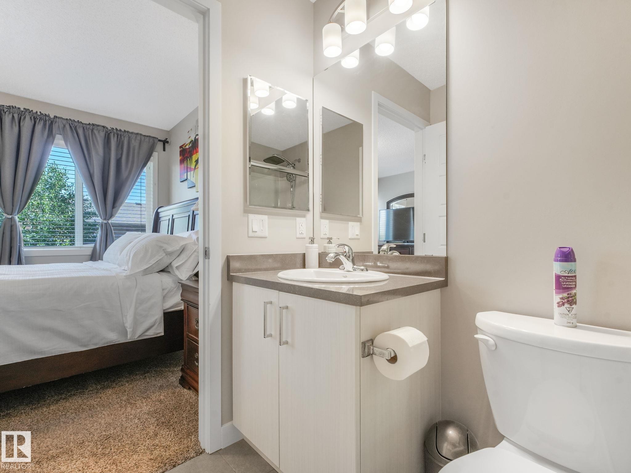 Compact bathroom featuring a white vanity with integrated sink, coordinating countertop, and wall-mounted mirror with overhead lighting - #55 4470 Prowse Rd Sw, Edmonton, AB - Indoor Photo Showing Bathroom