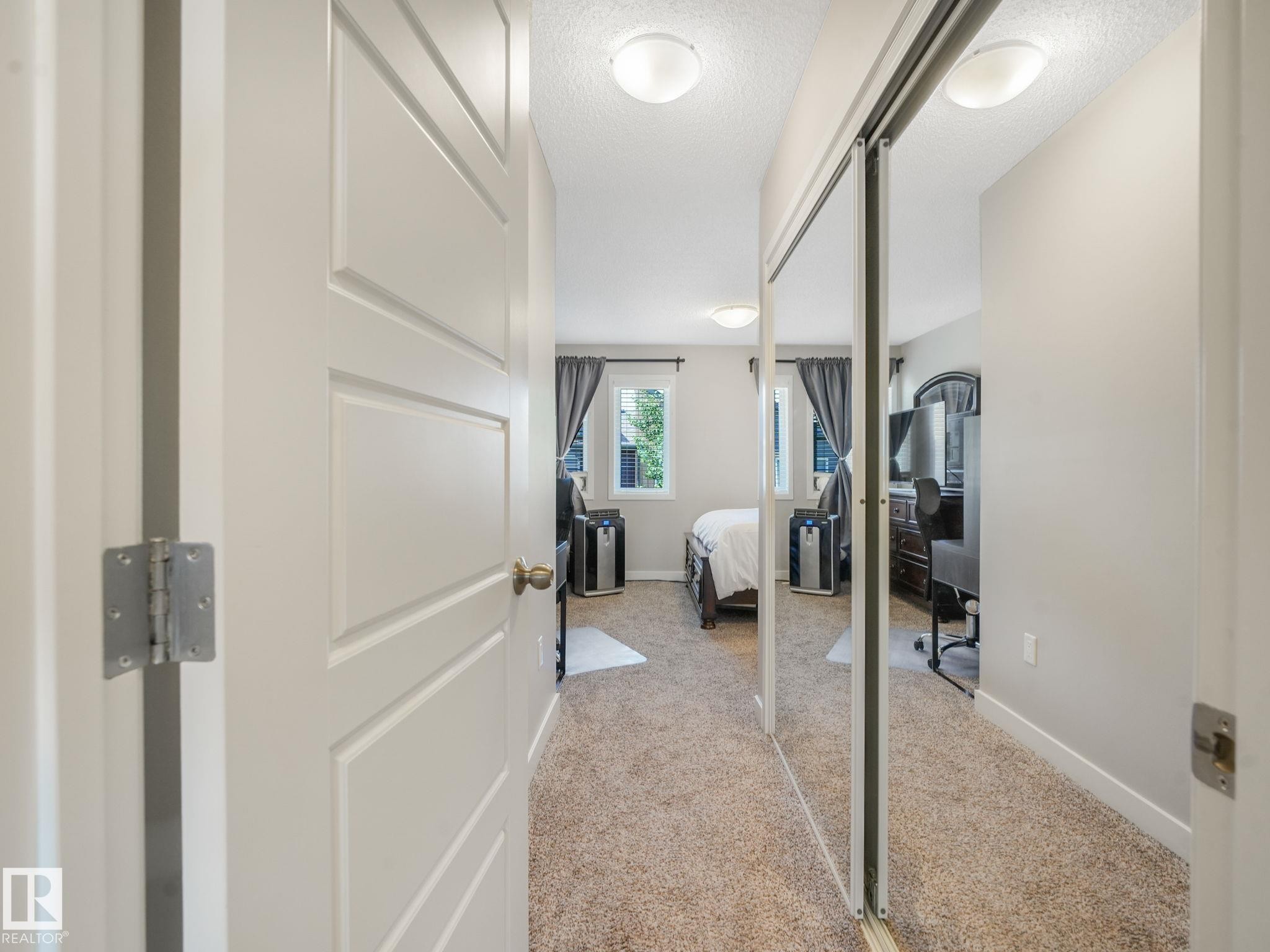 Bedroom featuring carpet flooring, two windows with drapery, and a mirrored closet door - #55 4470 Prowse Rd Sw, Edmonton, AB - Indoor Photo Showing Other Room
