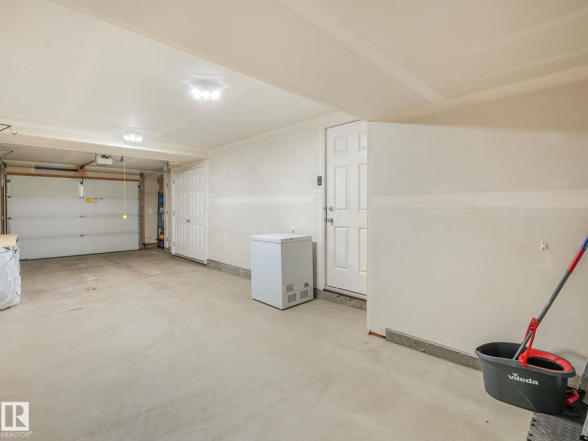 Attached two-car garage featuring a concrete floor, overhead lighting, and an access door - #55 4470 Prowse Rd Sw, Edmonton, AB - Indoor Photo Showing Garage