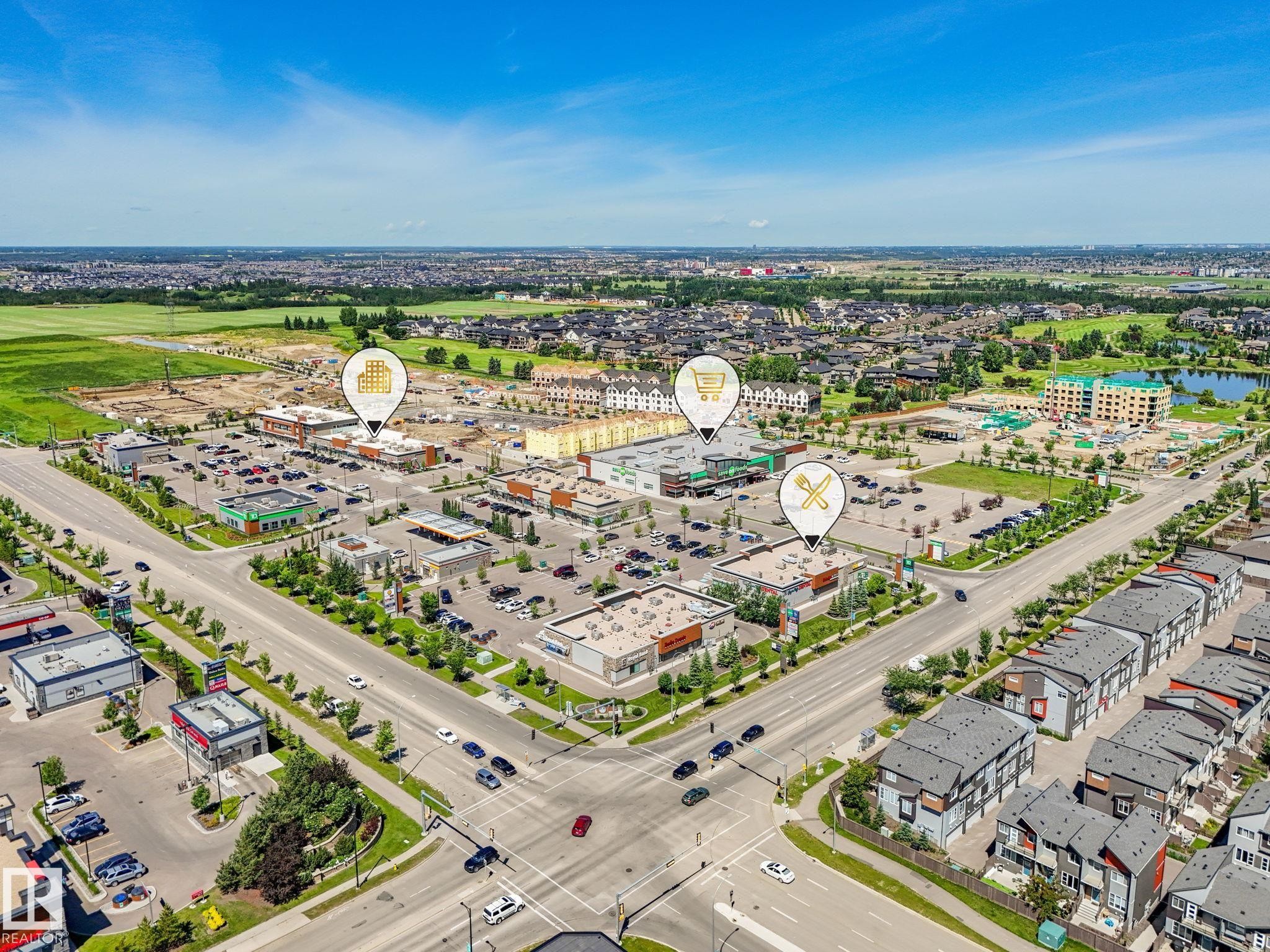 Aerial perspective showcasing a commercial development with multiple retail buildings, expansive parking areas, and mature landscaping - #55 4470 Prowse Rd Sw, Edmonton, AB - Outdoor With View