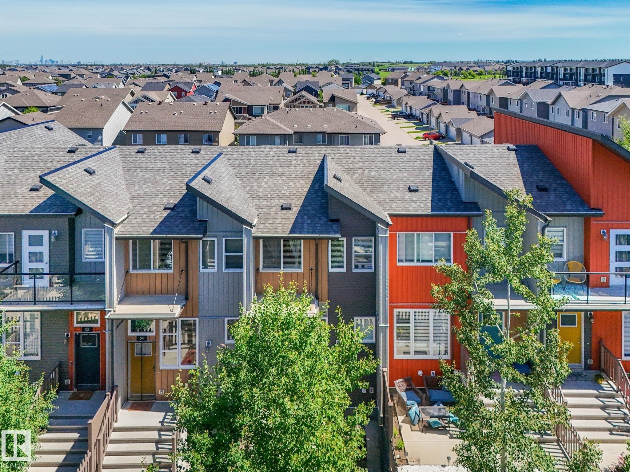 Contemporary townhome exterior featuring multi-toned siding, gabled roofs, and an upper-level balcony with glass railing - #55 4470 Prowse Rd Sw, Edmonton, AB - Outdoor With Facade