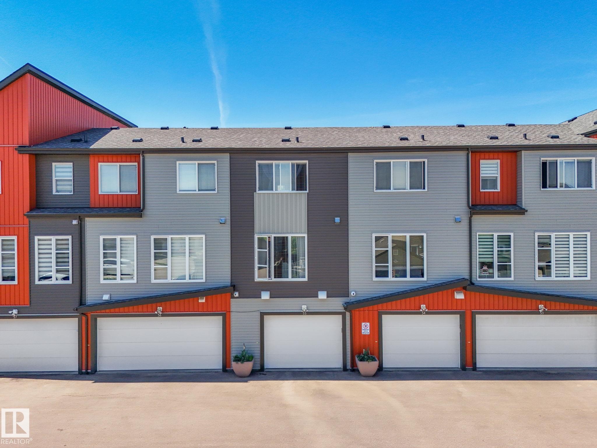 Modern townhouse exterior featuring multi-toned siding in gray, charcoal, and vibrant orange accents - #55 4470 Prowse Rd Sw, Edmonton, AB - Outdoor