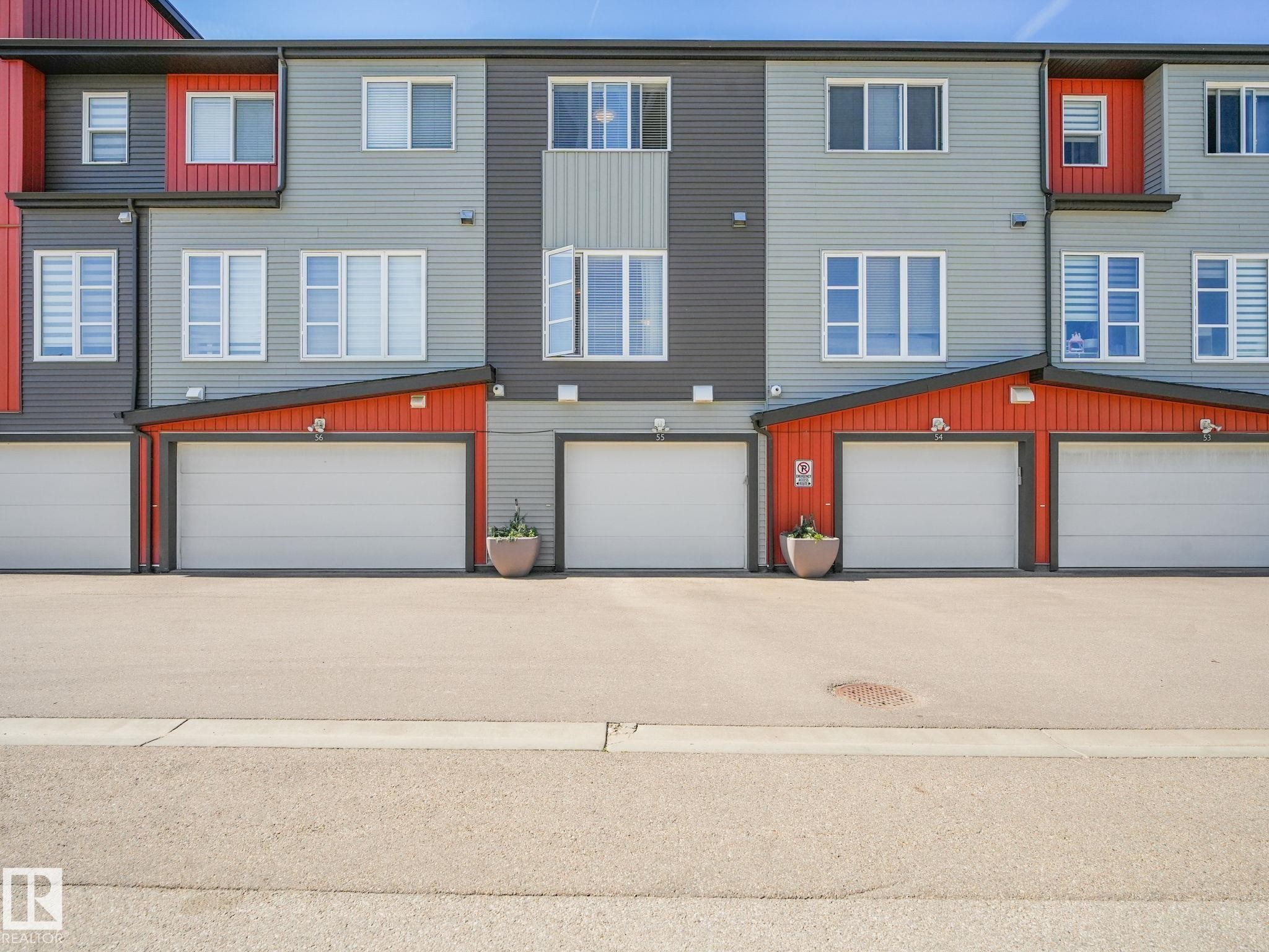 Contemporary townhome exteriors featuring horizontal siding in gray and charcoal tones, accented with orange panels - #55 4470 Prowse Rd Sw, Edmonton, AB - Outdoor