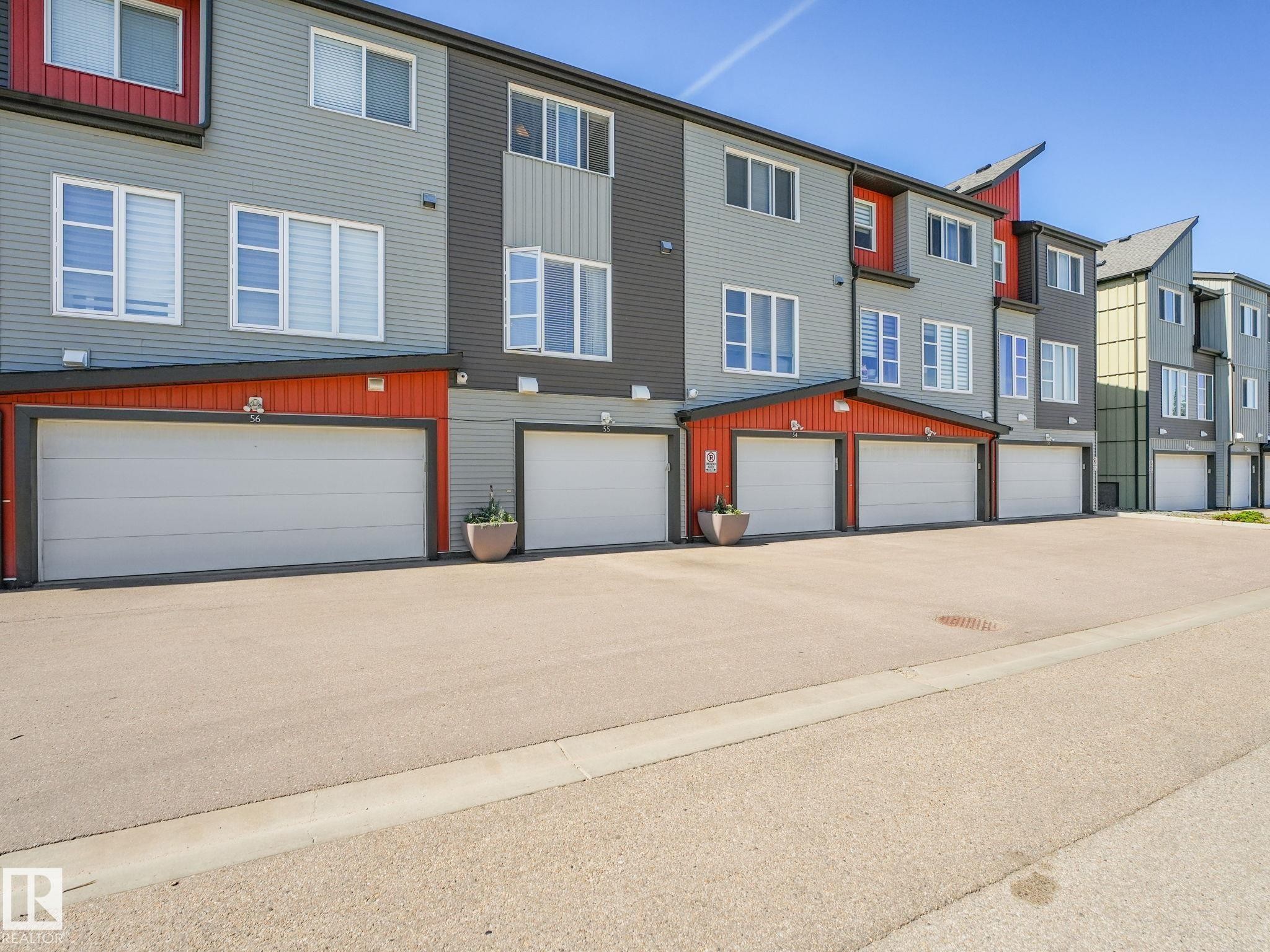 Modern townhome-style residences featuring multi-toned siding, white-framed windows, and individual garage access - #55 4470 Prowse Rd Sw, Edmonton, AB - Outdoor