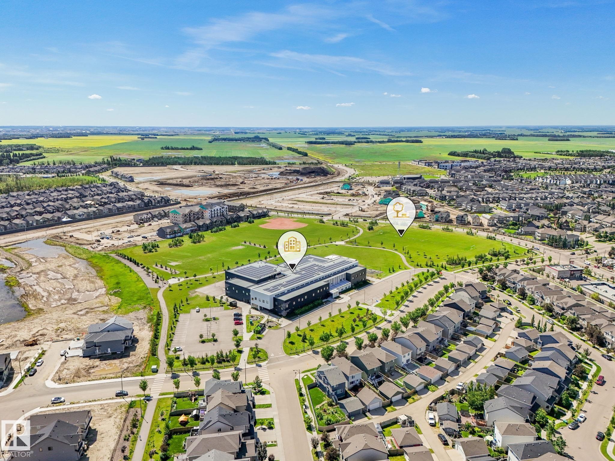 Aerial perspective showcasing a residential development with extensive green spaces - #55 4470 Prowse Rd Sw, Edmonton, AB - Outdoor With View