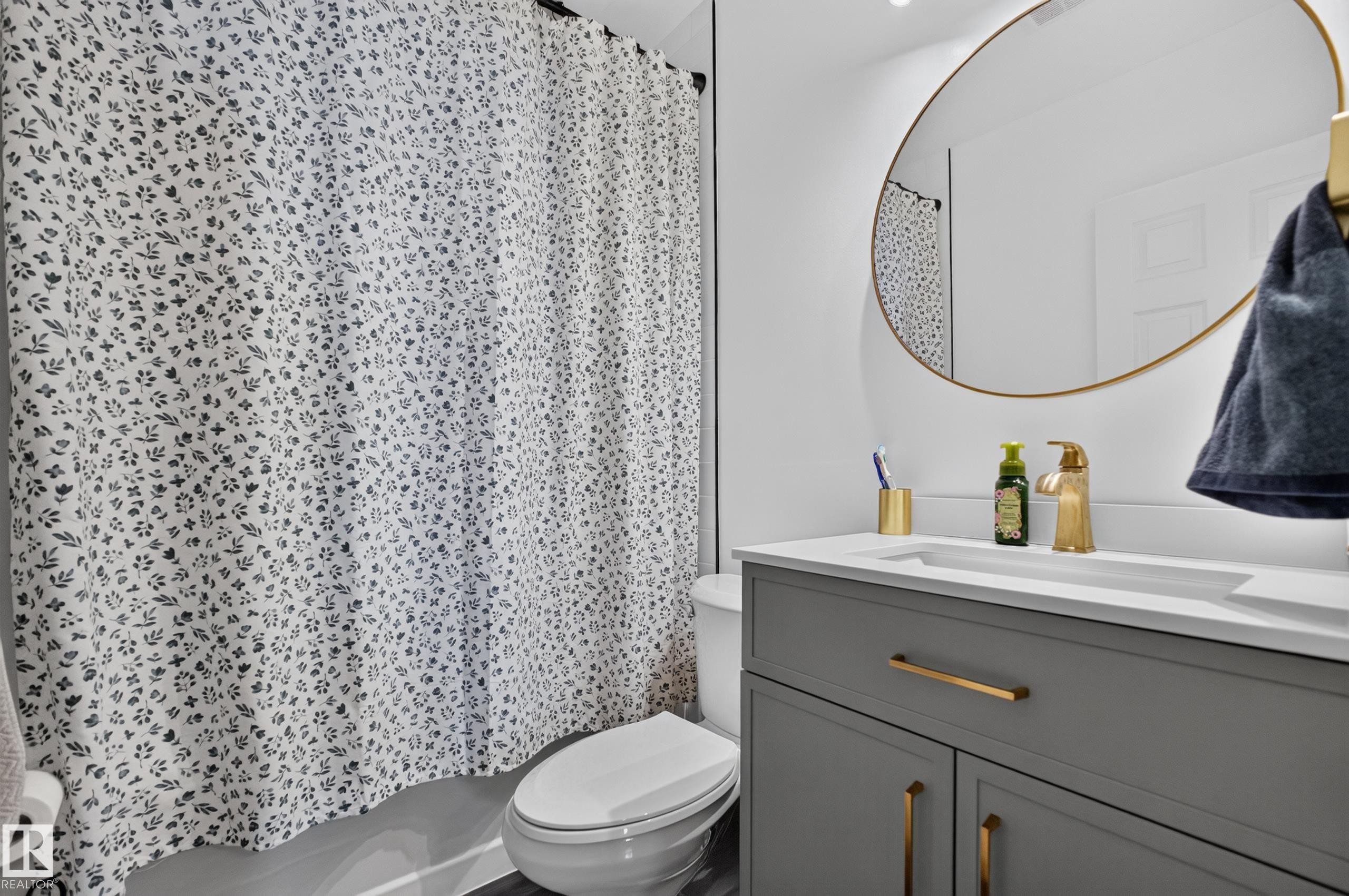 Bathroom vanity with an integrated sink, white countertop, and gold-finish faucet - 11015 122 Street, Edmonton, AB