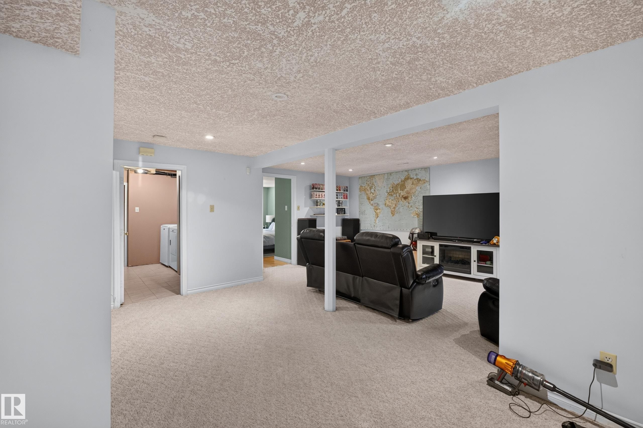 Expansive entertainment area featuring recessed lighting, light-toned carpeting, and a built-in media console with fireplace insert - 11015 122 Street, Edmonton, AB