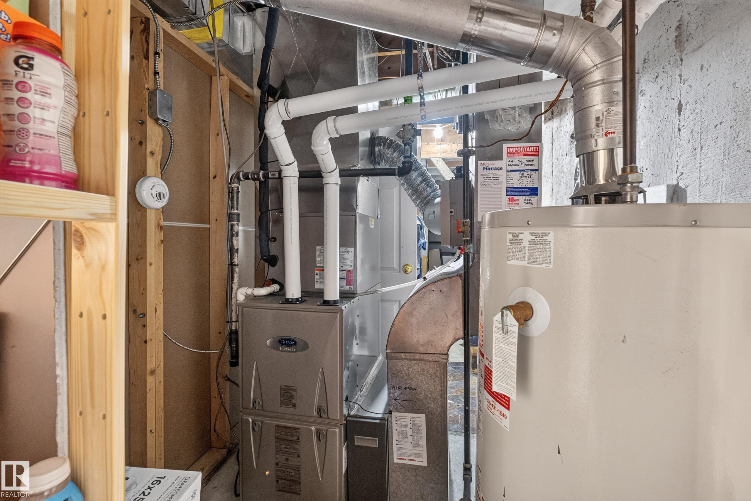 Utility area featuring a Carrier furnace and a water heater, with exposed wood framing and concrete block walls - 11015 122 Street, Edmonton, AB