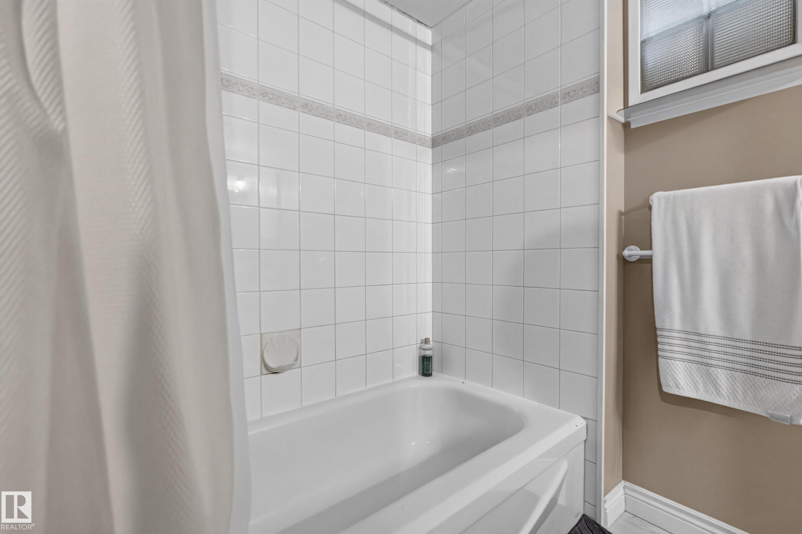 White tiled bath and shower combination with decorative accent tile band - 11015 122 Street, Edmonton, AB