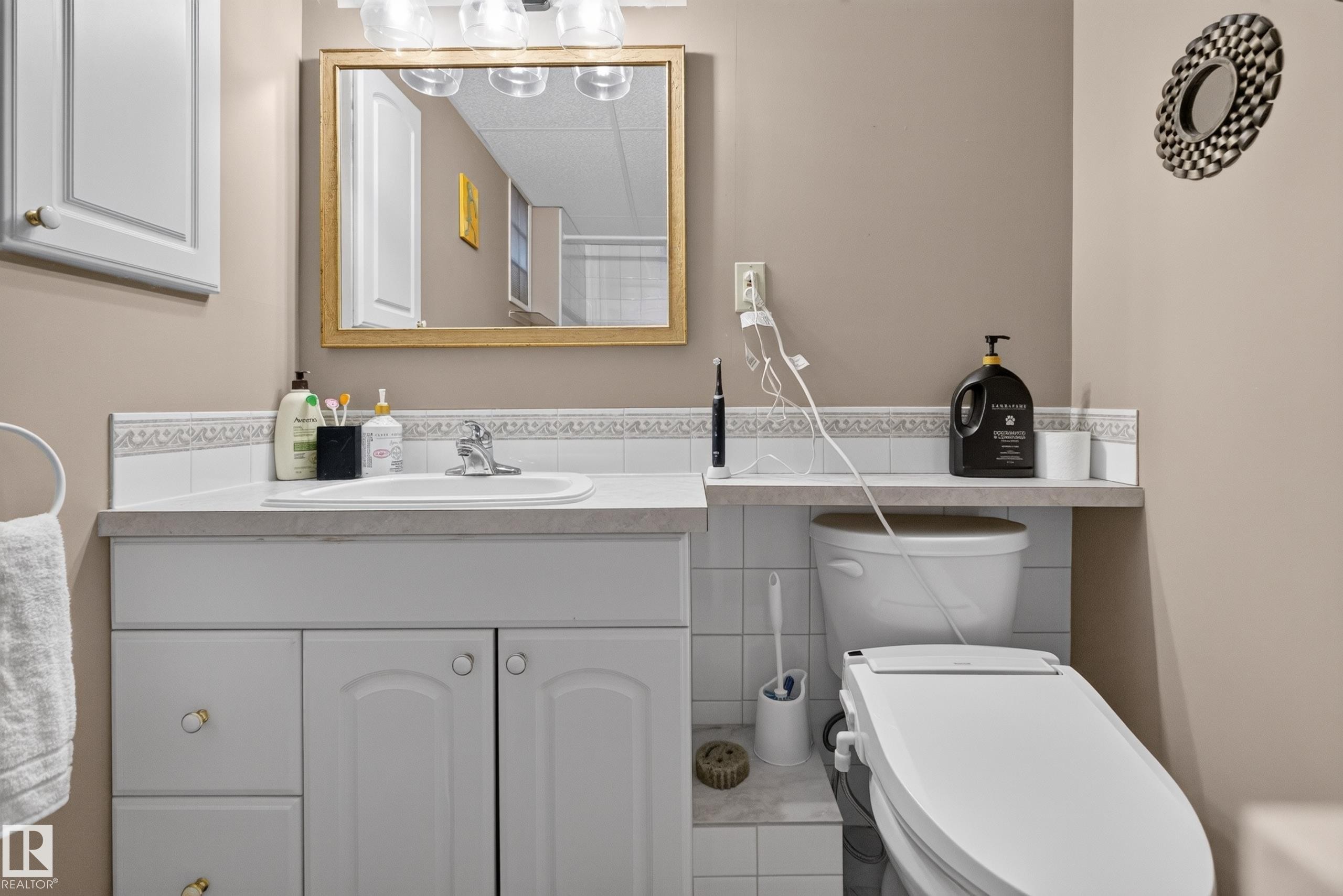 Bathroom featuring a single vanity with white cabinetry, a built-in sink, and a light-toned countertop - 11015 122 Street, Edmonton, AB
