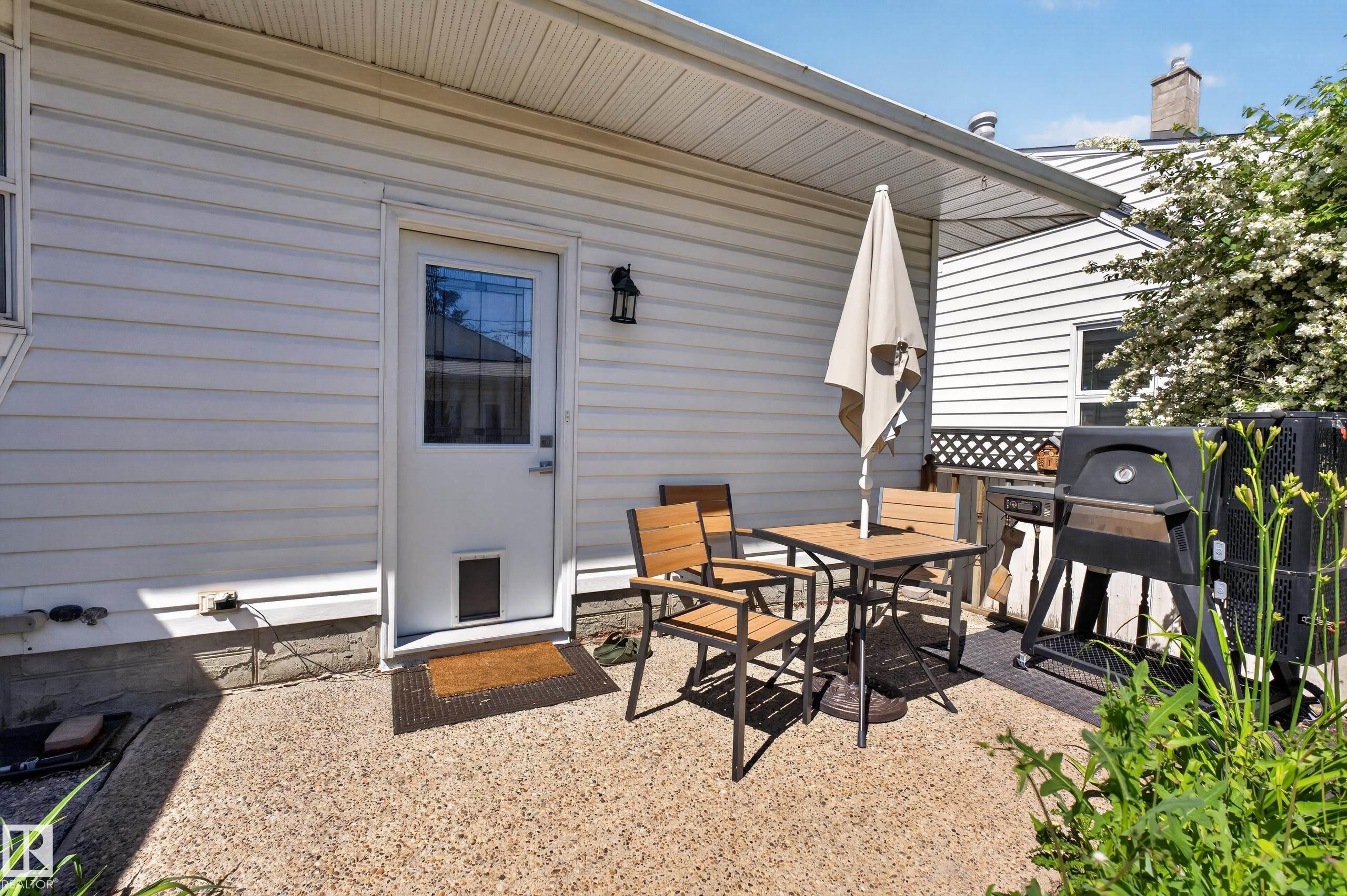 Exterior patio featuring a textured concrete surface and white vinyl siding - 11015 122 Street, Edmonton, AB