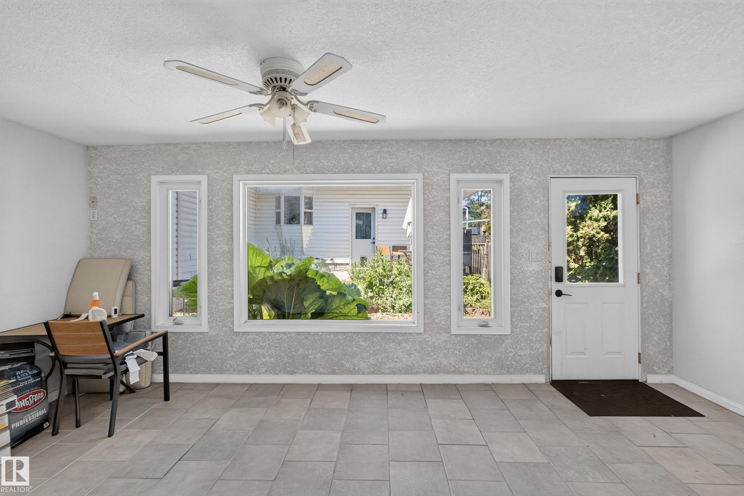 Sunroom featuring light-toned tile flooring, textured wall finish, and a ceiling fan - 11015 122 Street, Edmonton, AB