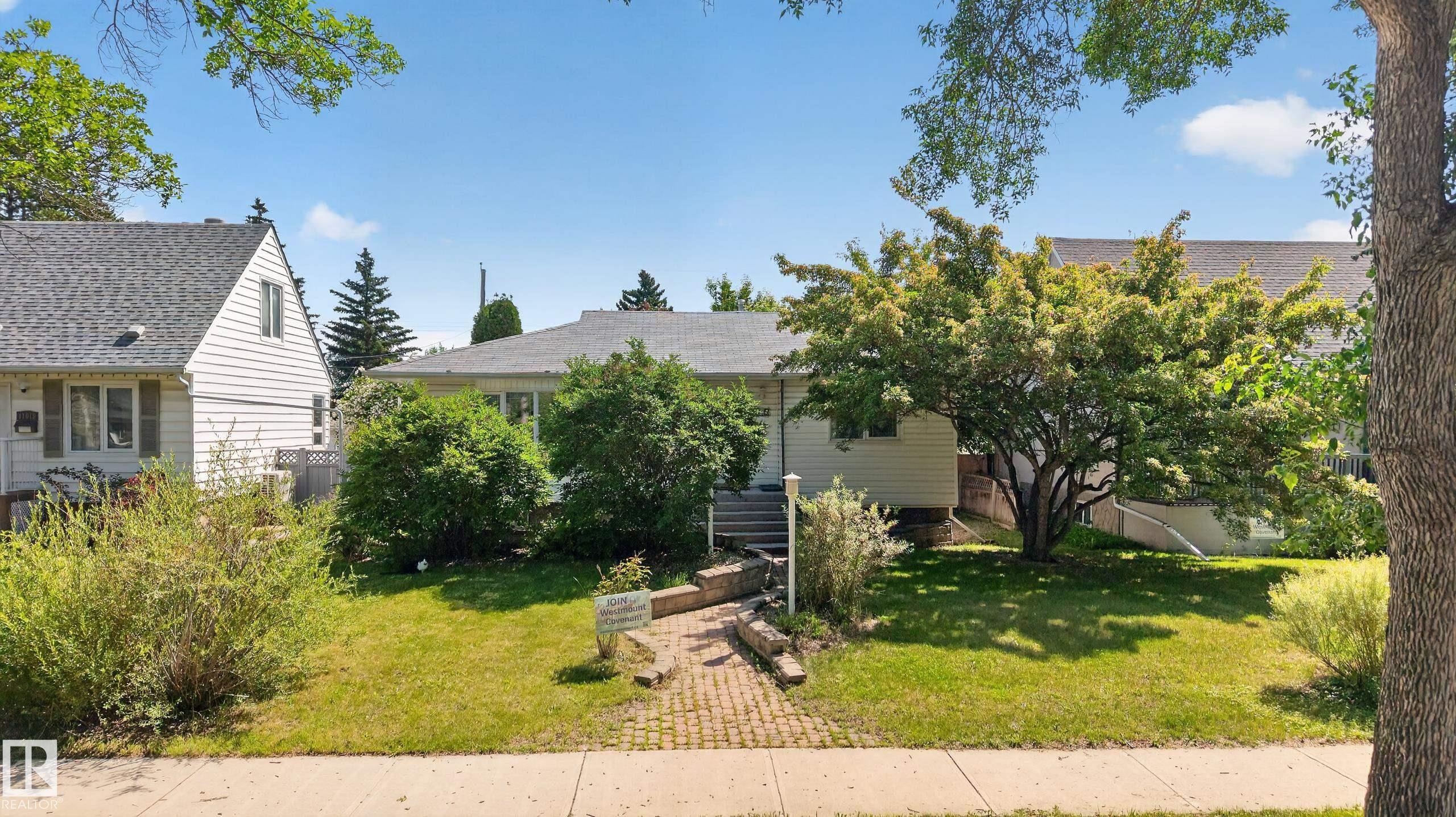 Front exterior featuring a white siding facade, gray shingle roof, and a mature tree - 11015 122 Street, Edmonton, AB