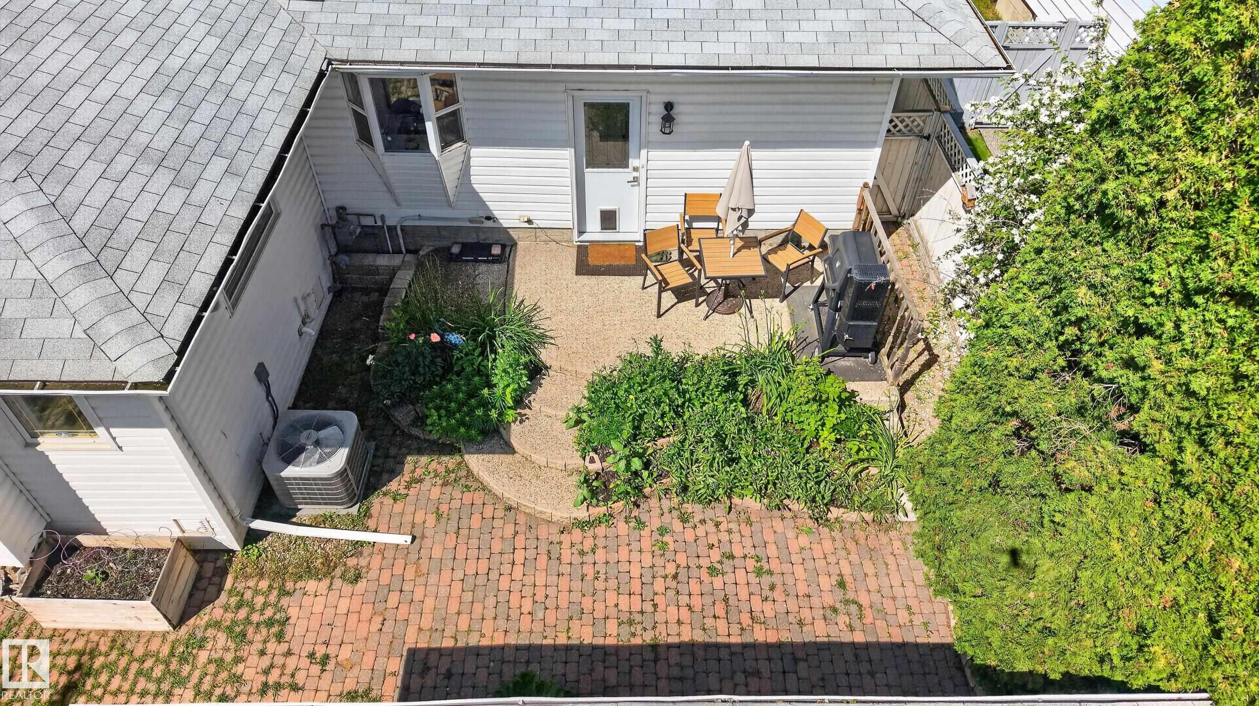 Rear exterior featuring a white siding finish, shingle roofing, and a concrete patio area - 11015 122 Street, Edmonton, AB