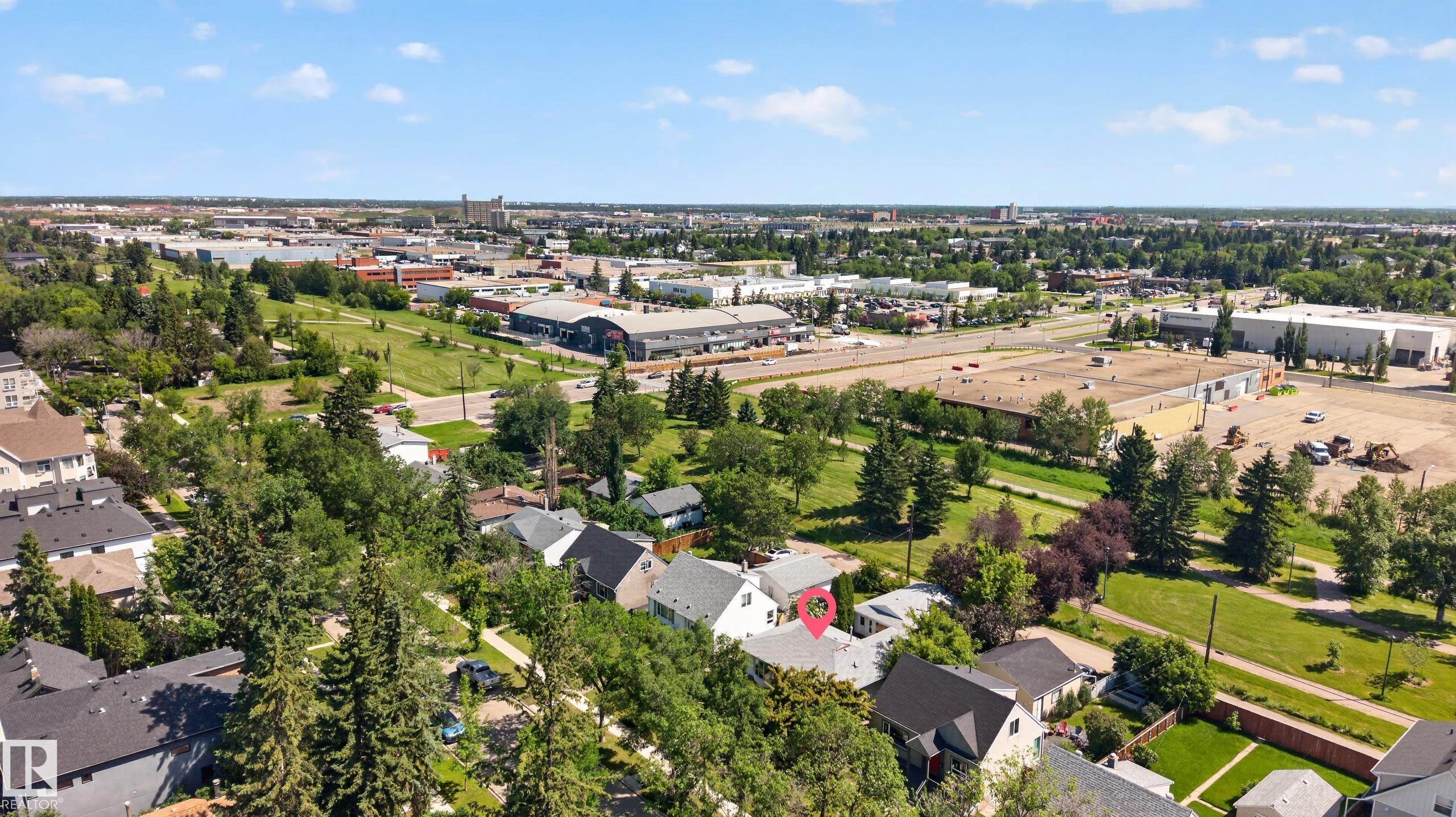 Aerial perspective showcasing a residential property with a light-colored roof, surrounded by mature trees - 11015 122 Street, Edmonton, AB