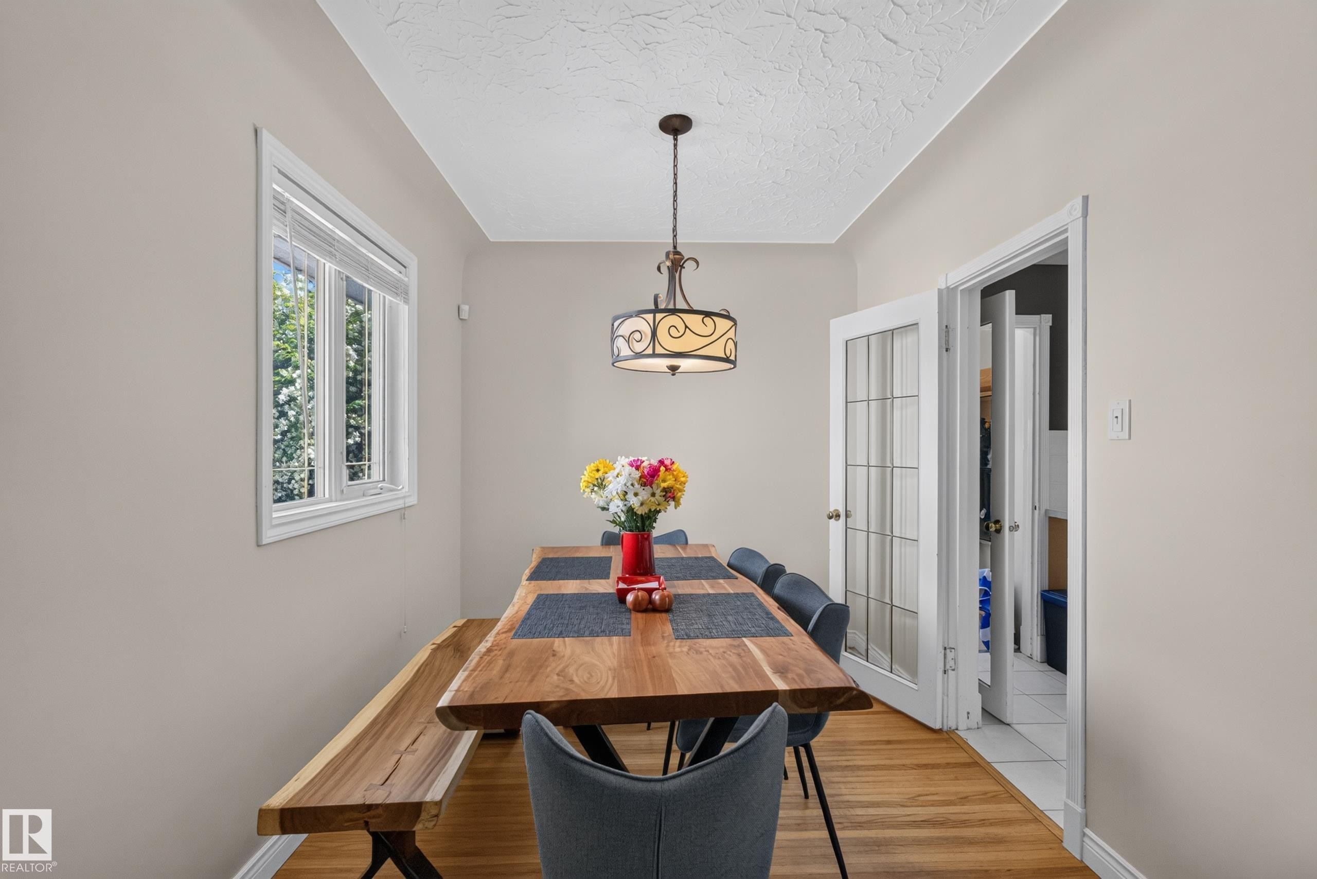 Bright room featuring wood-finish flooring, a white-framed window, a decorative ceiling light fixture, and French doors with glass panes - 11015 122 Street, Edmonton, AB