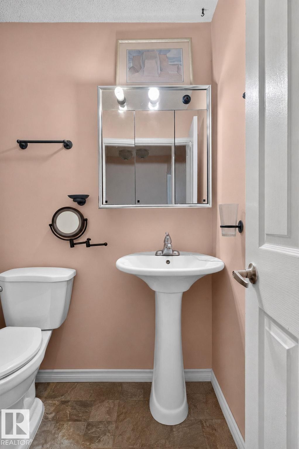 Pedestal sink with chrome faucet, complemented by a mirrored medicine cabinet with integrated lighting - 8316 157 Avenue, Edmonton, AB